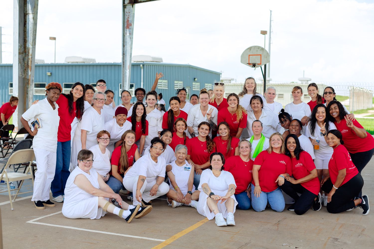Group of volunteers wearing red and white shirts gathered outdoors for a community service event.