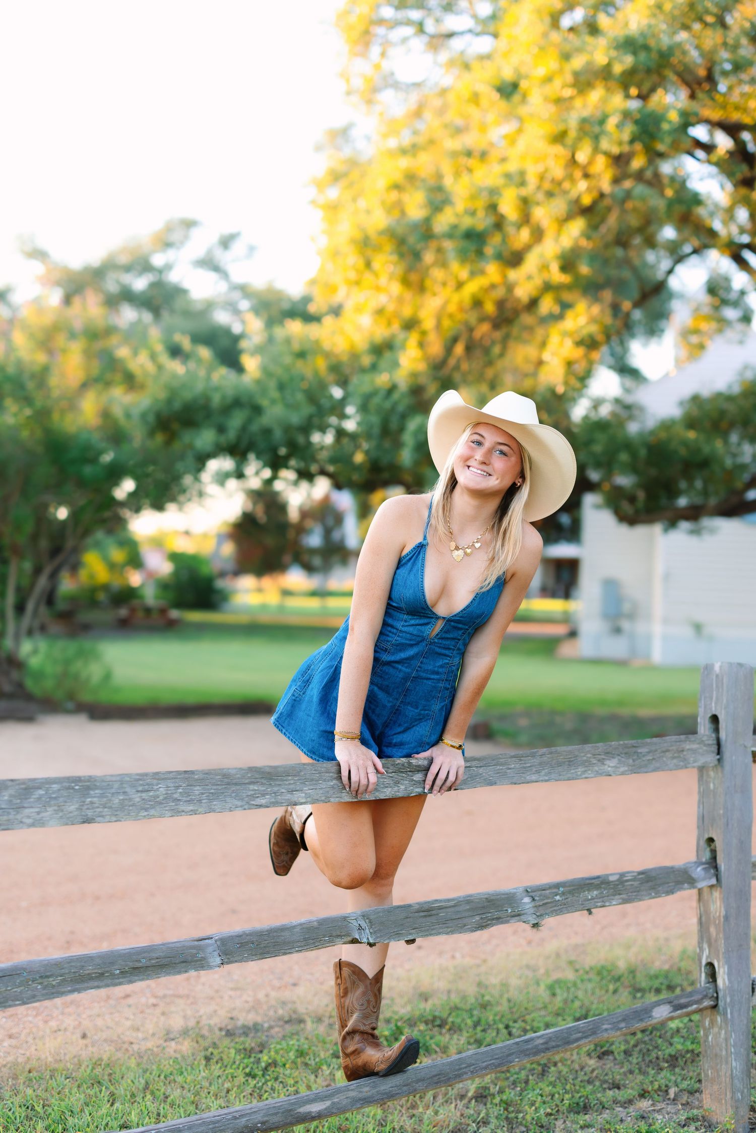 A blue dress and cowboy boots ensemble is styled with a fence pose at sunset.