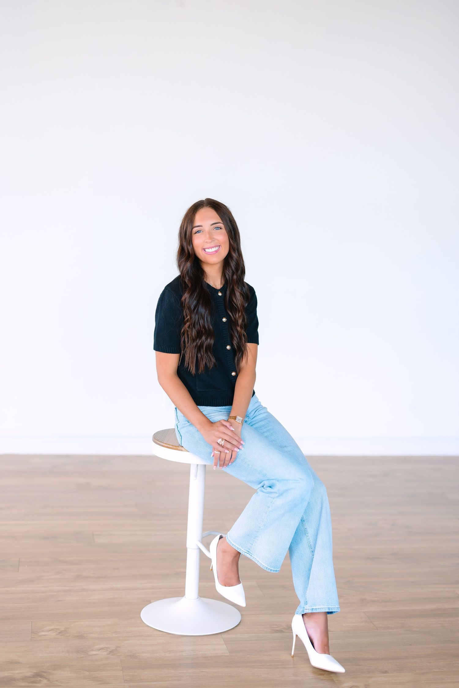 Casual lifestyle photo of someone sitting on white chair wearing jeans and black top.