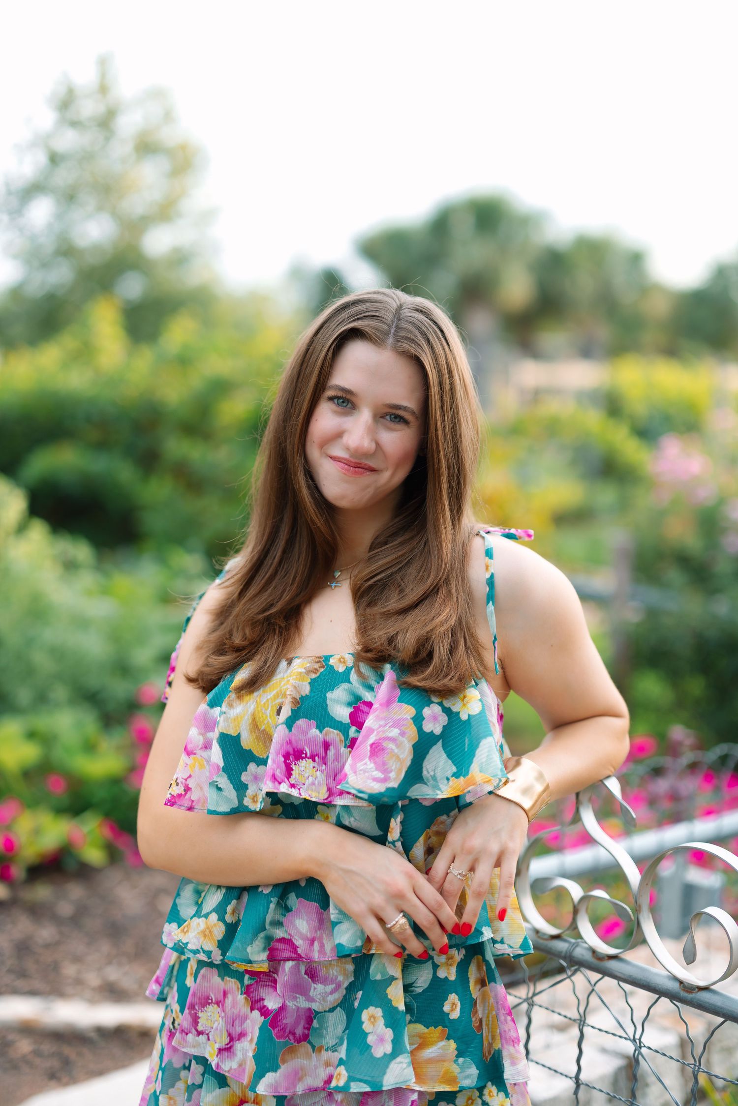 Floral dress portrait session in blooming garden with decorative metal fence.