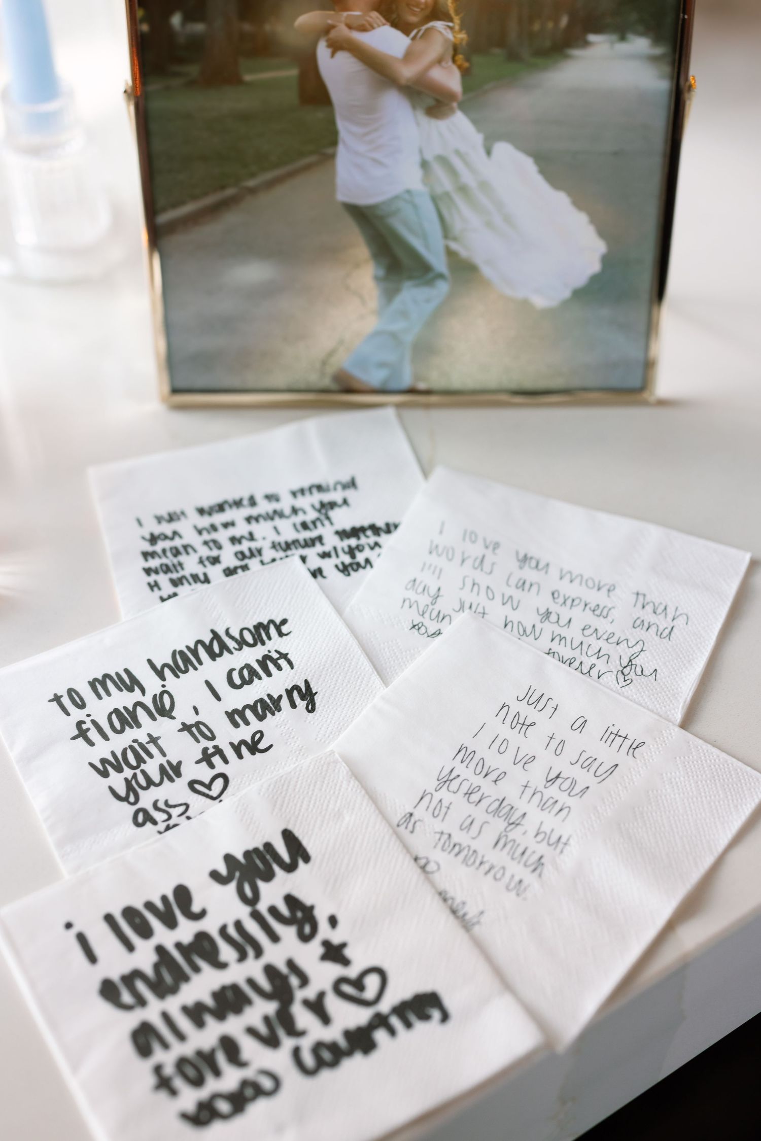 Handwritten love notes on napkins with a framed couple photo, wedding keepsakes for Matt and Courtney.