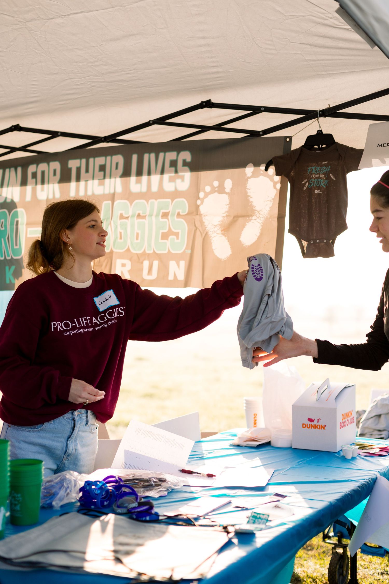 Registration tent setup with t-shirts and supplies for charity run event.