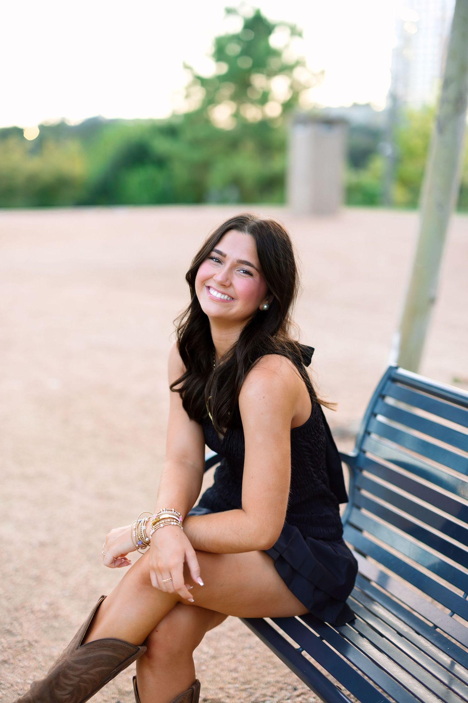 Relaxed outdoor portraits on a park bench wearing a black dress and brown boots.