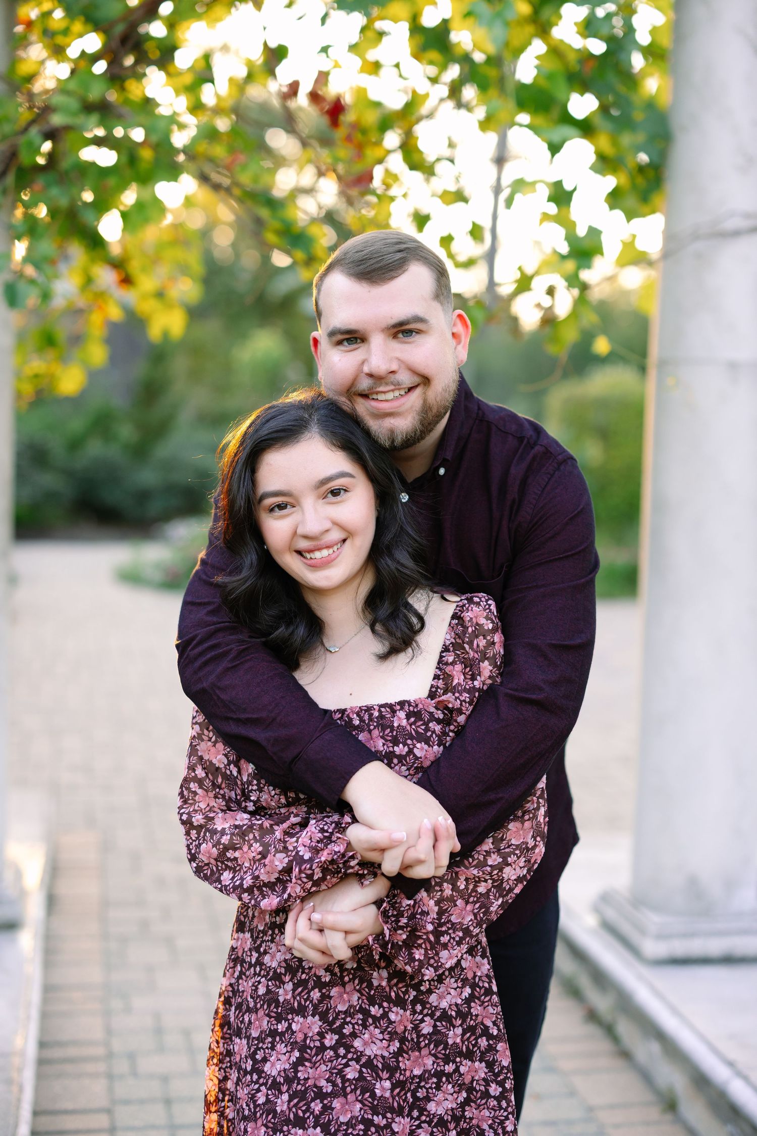A couple embraces in a romantic outdoor photoshoot wearing coordinated purple and floral outfits.