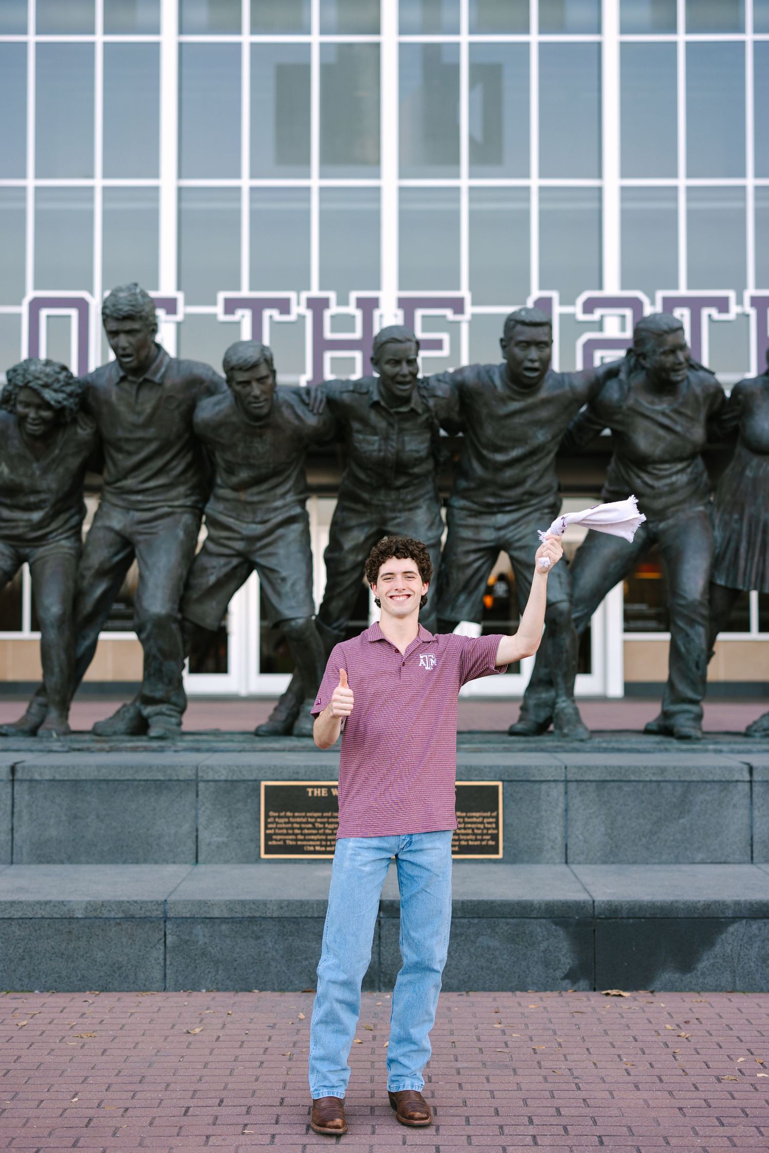 Student poses playfully in front of row of bronze statues on campus.