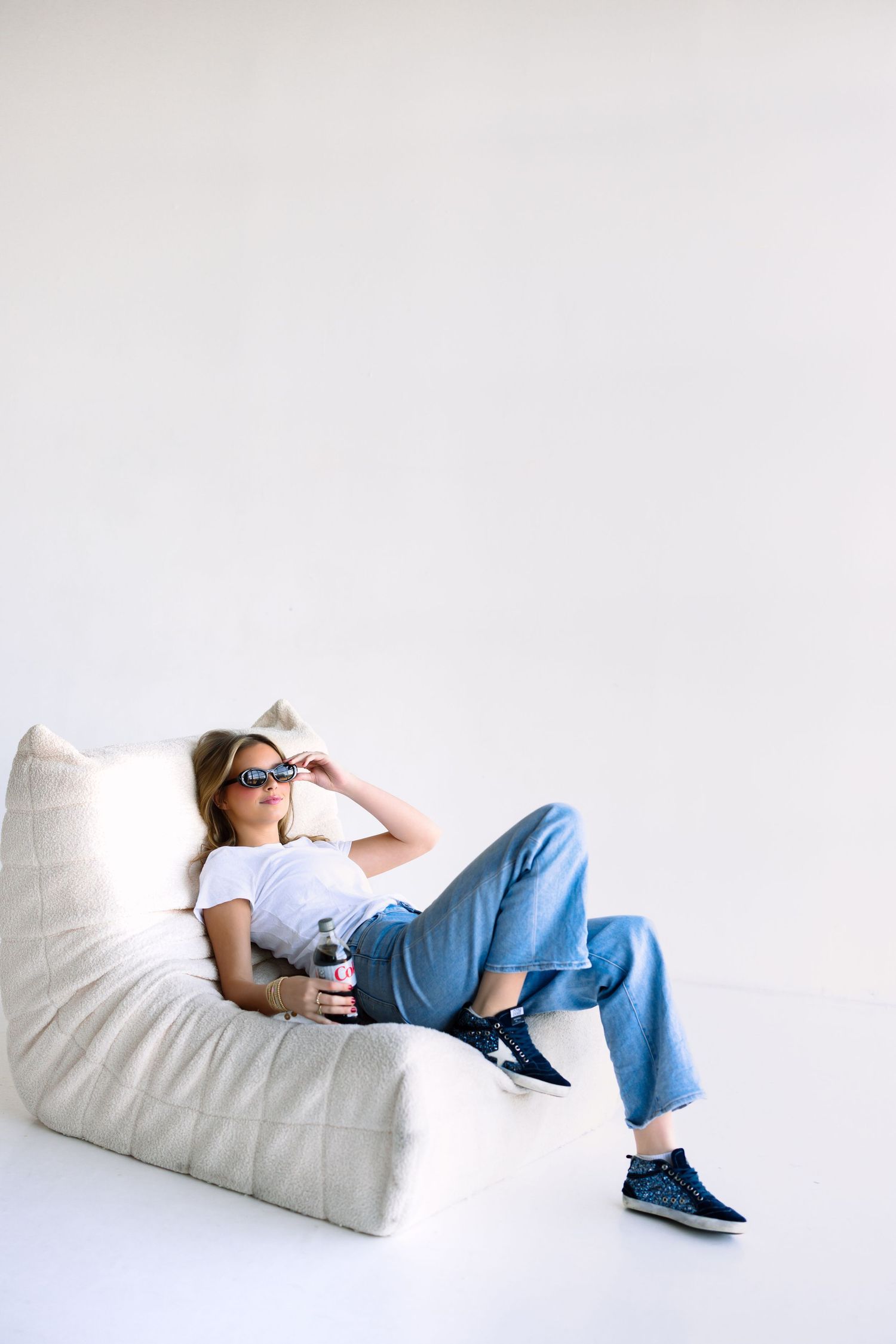 Relaxed lifestyle photo on beanbag chair wearing sunglasses and holding drink.