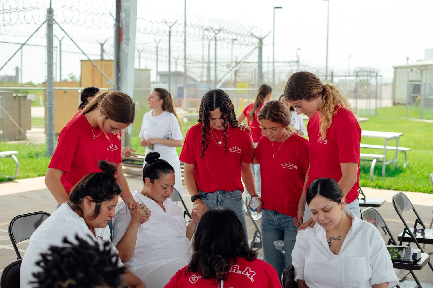 Volunteers in red shirts participating in an outdoor prison ministry event.