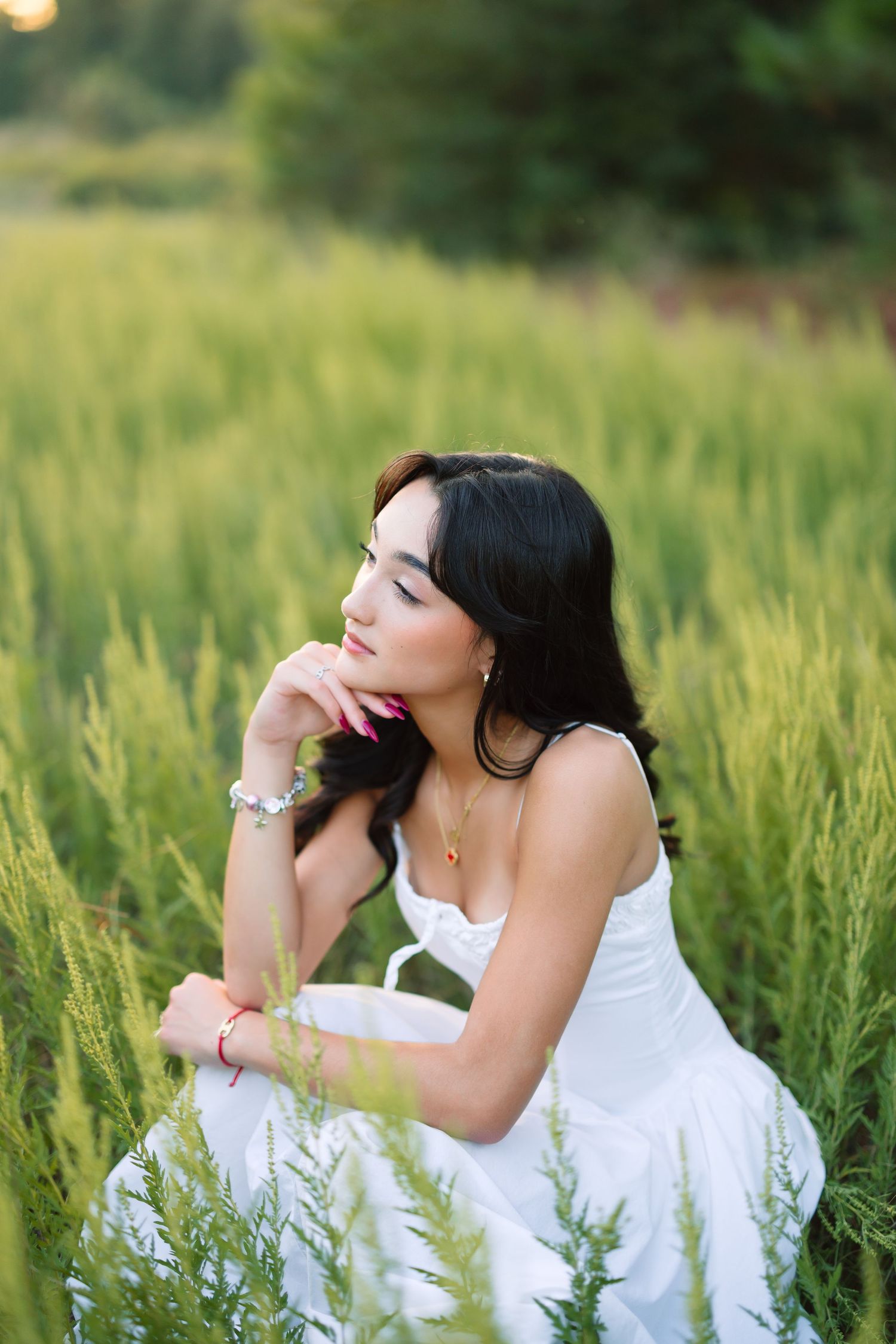 Dreamy poses in a white dress surrounded by tall grass during sunset.