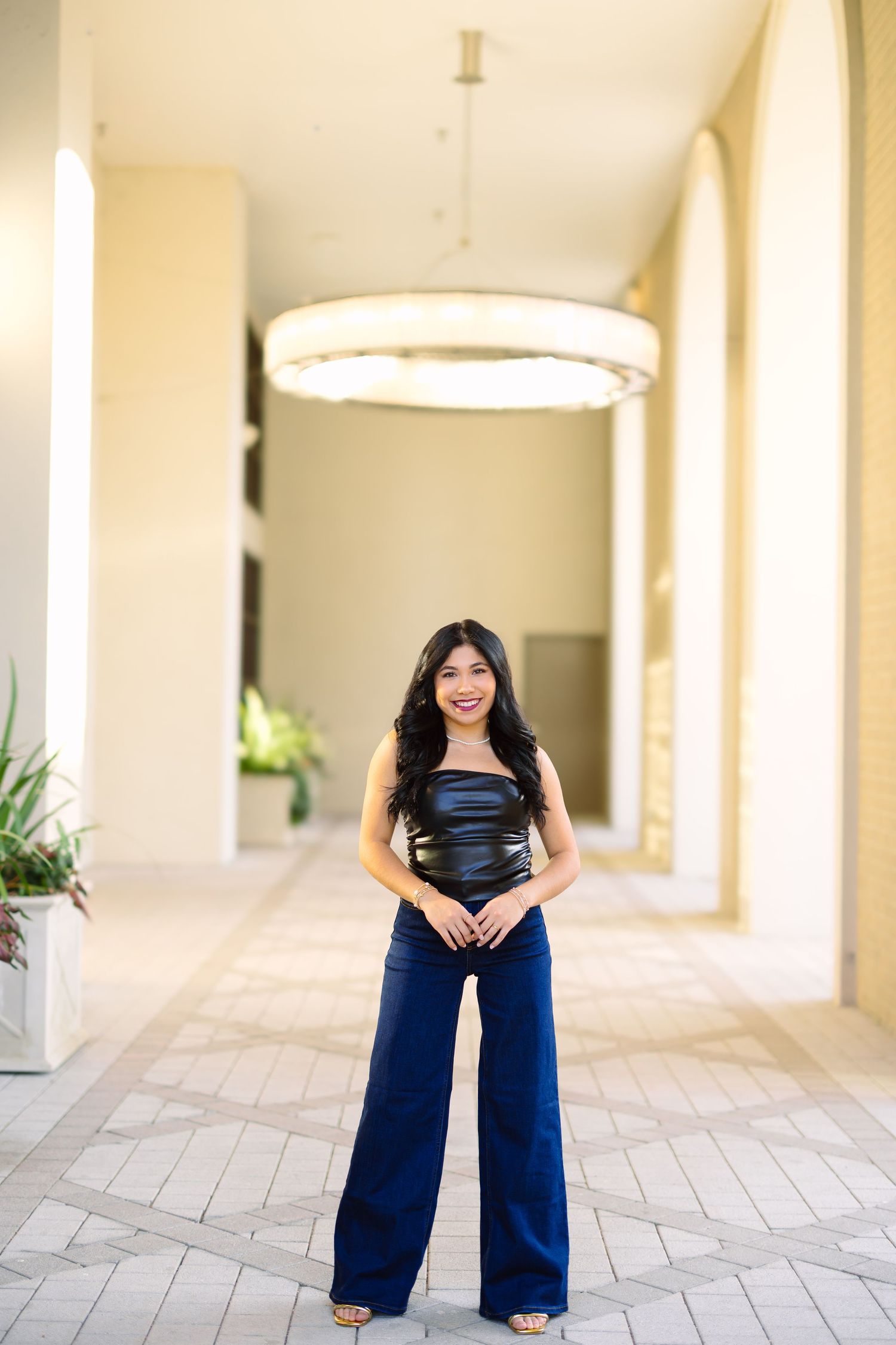 A series of four photos showing a person in a black top and navy pants posing in an outdoor corridor with arches.