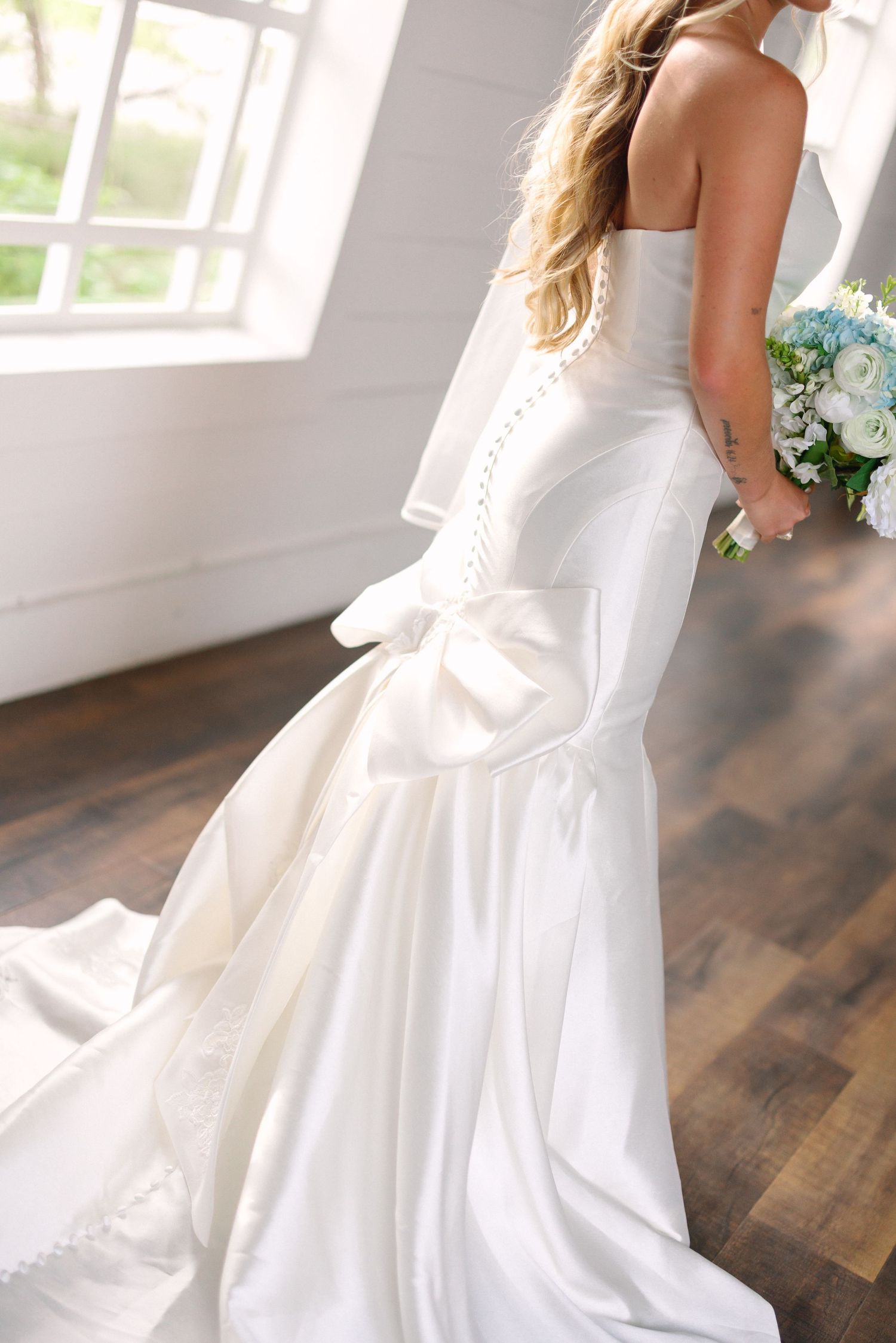 A flowing white wedding dress twirls gracefully on a dark wooden floor.
