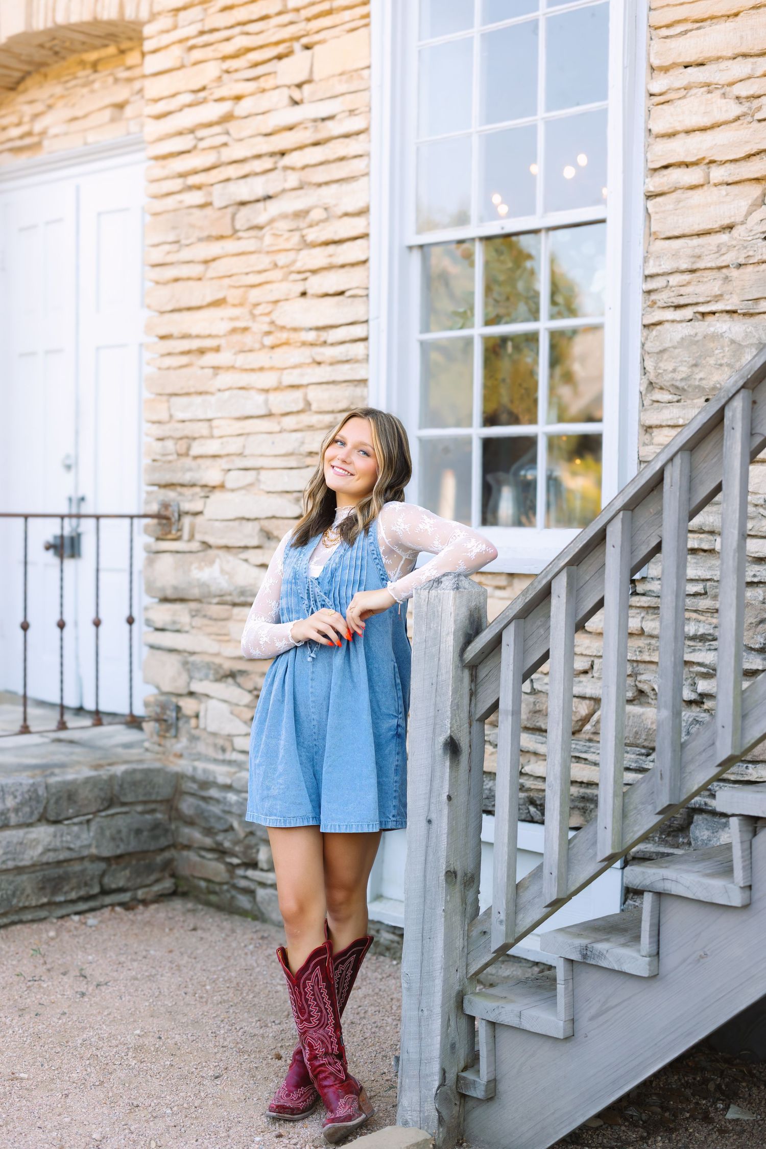 A denim dress and burgundy boots are featured on stone steps of a historic building.