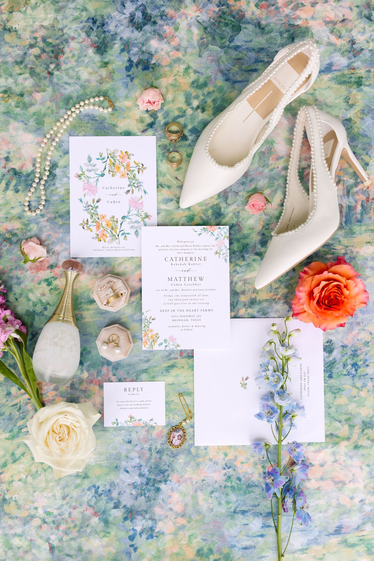 Elegant wedding flat lay with floral invitations, pearl heels, roses, and jewelry on a watercolor backdrop.