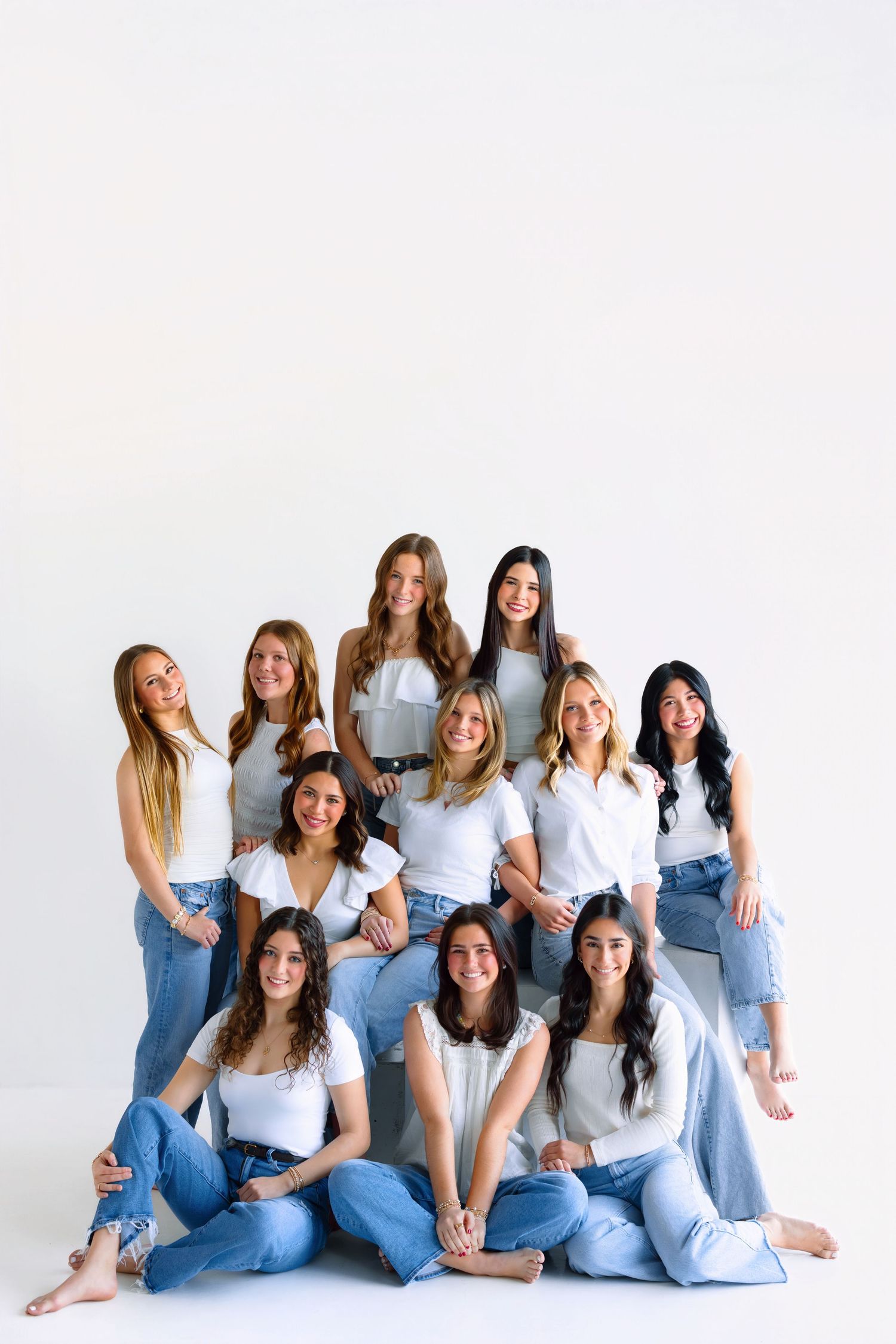 Women in coordinated white shirts and jeans posing casually on white backdrop.