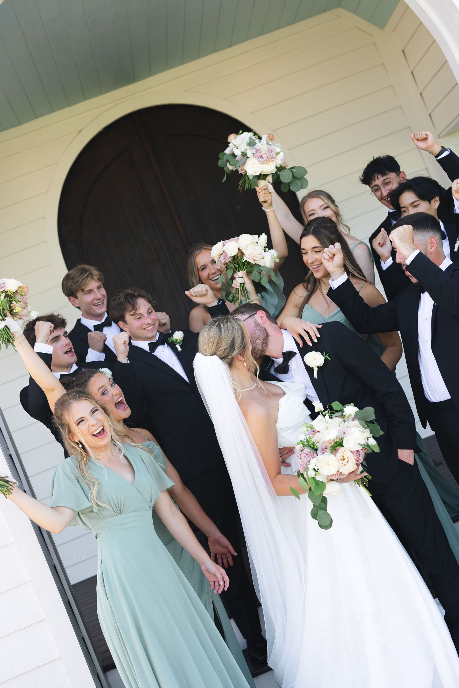 Joyful wedding party celebrating and laughing together on a white porch.