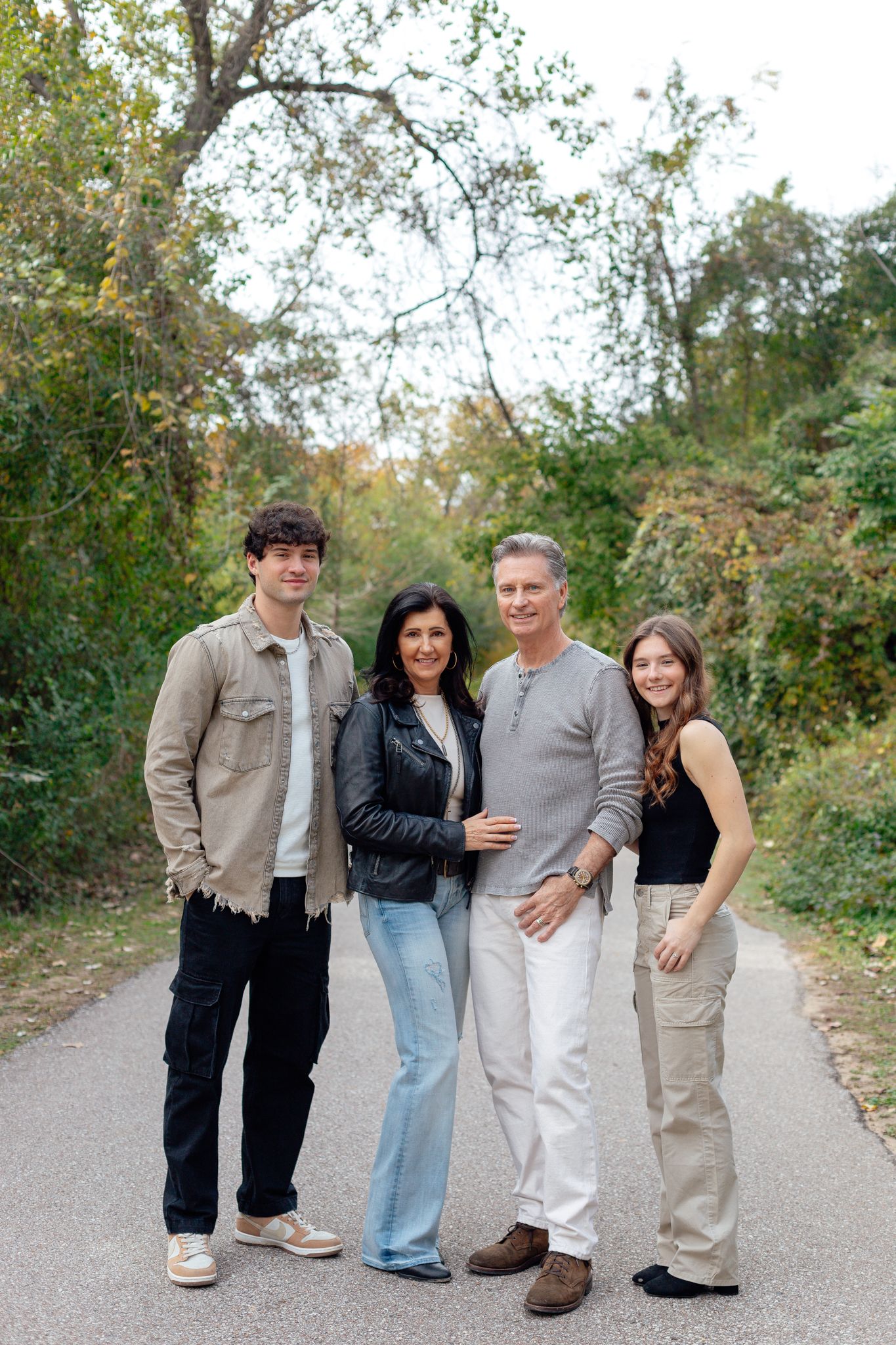A family group poses together on a tree-lined path during autumn.