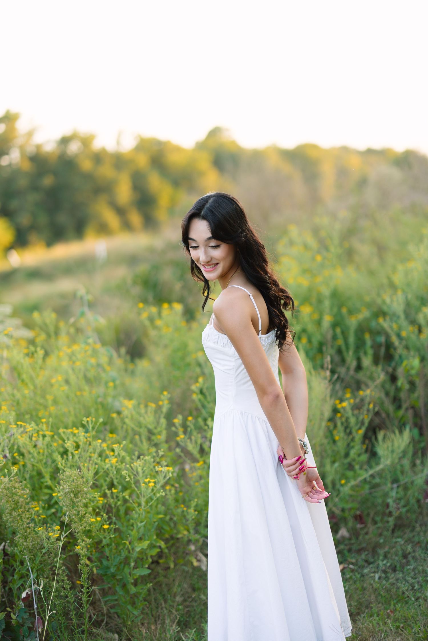 Carefree poses in a white sundress among wildflowers at golden hour.