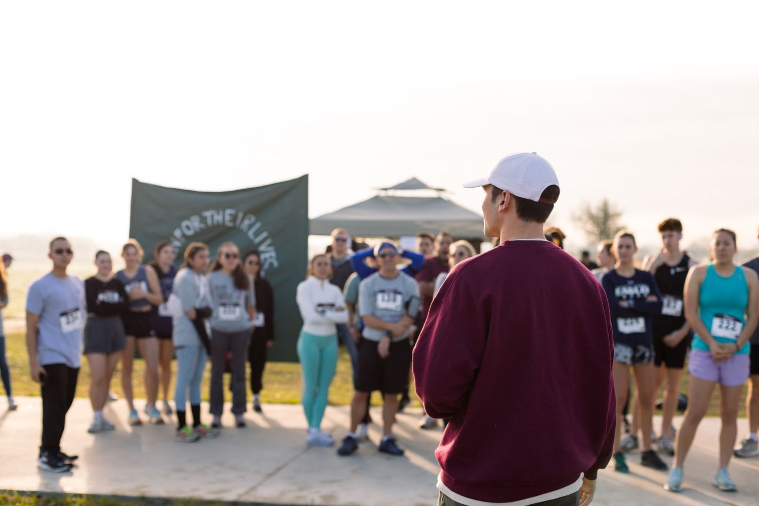 Group of people standing together outdoors wearing casual clothing and maroon shirts.