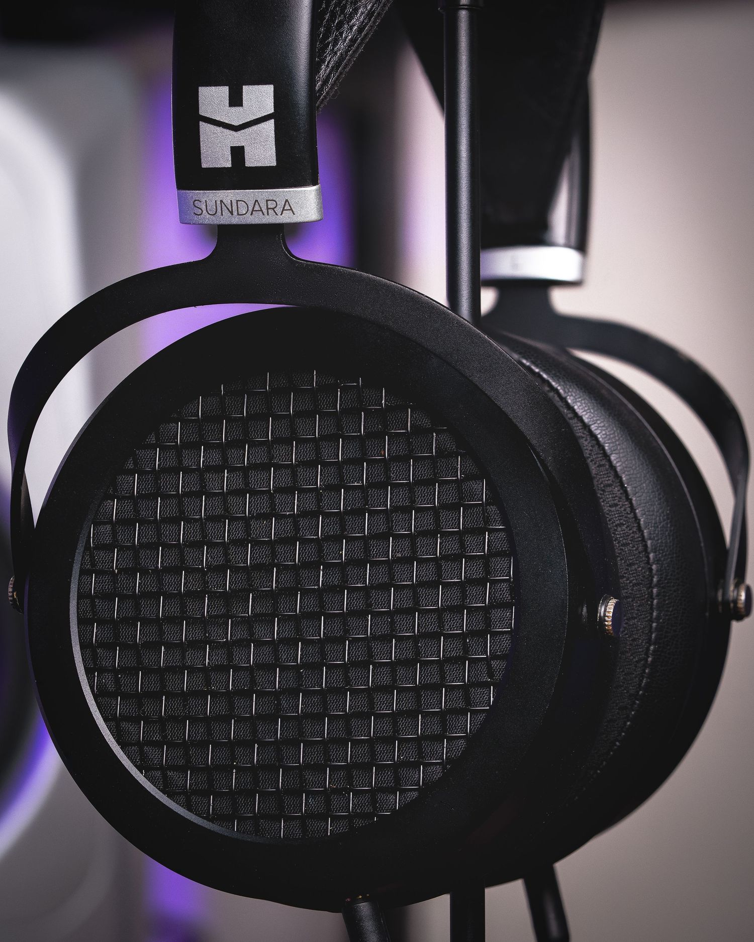 Close-up macro shot of black planar magnetic headphone driver with honeycomb pattern and purple lighting.