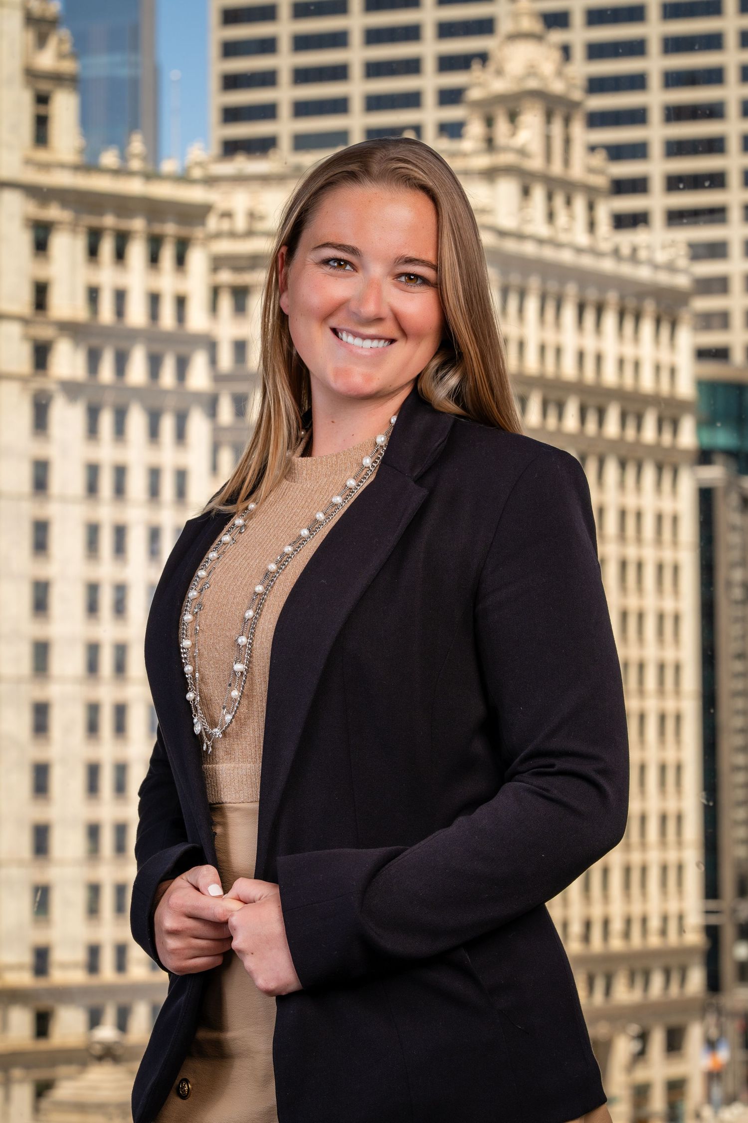 Business portraits showing professional in black blazer and beige top against urban backdrop.