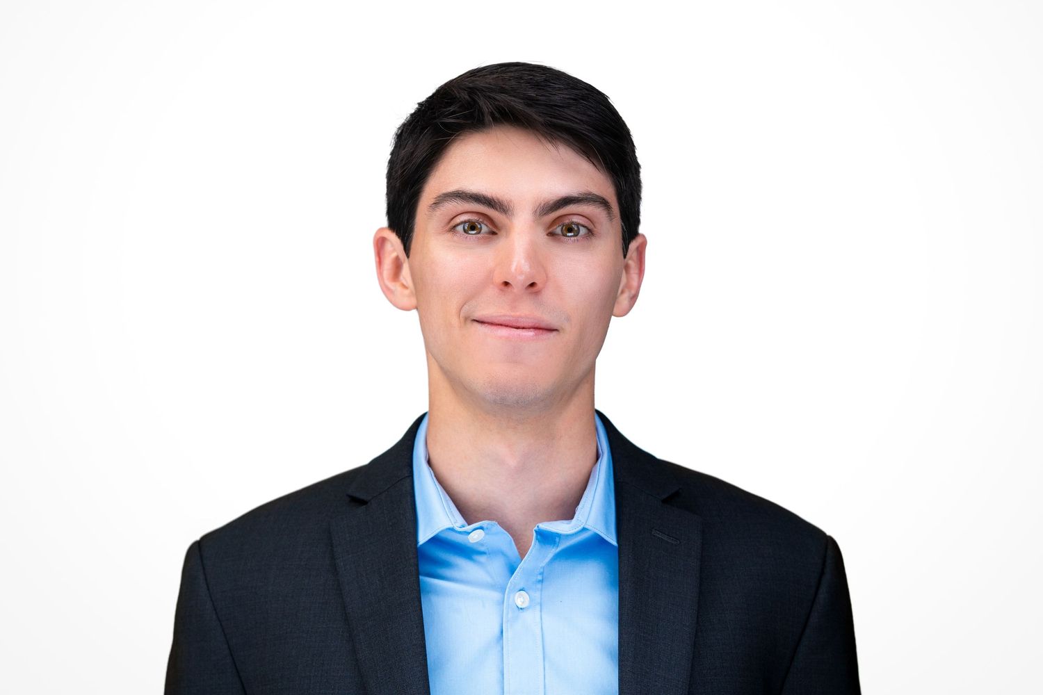 Professional headshot of a person in a dark suit jacket and light blue dress shirt against a white background.
