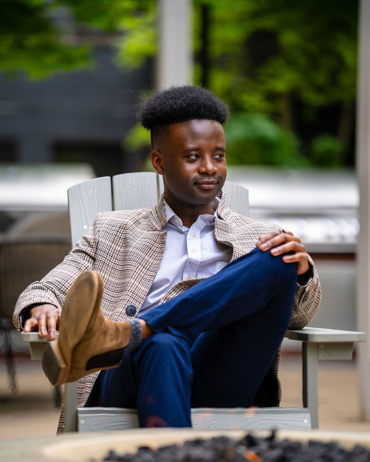 Person in brown plaid jacket relaxing in outdoor seating area.