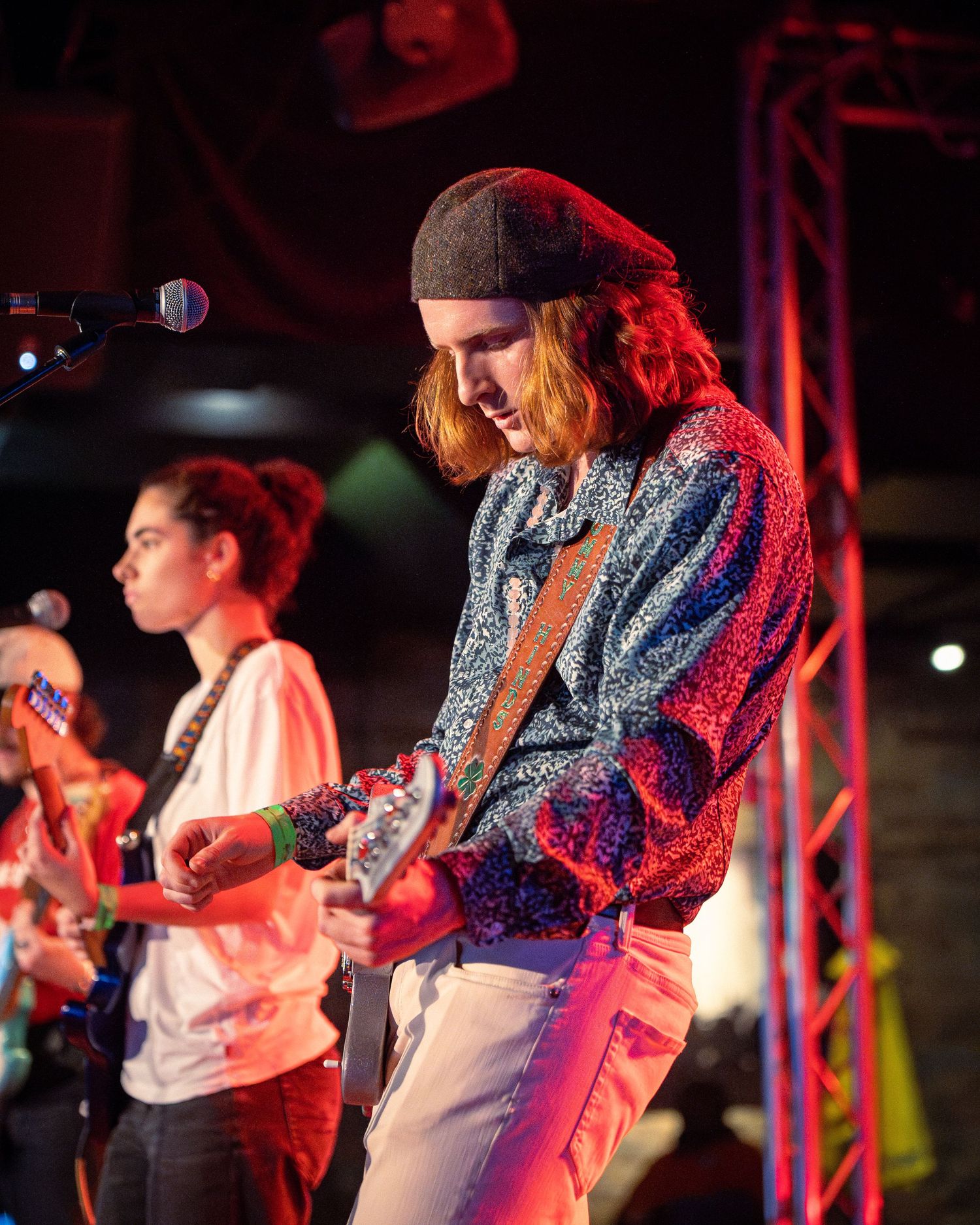Band members play instruments on stage with colorful lighting and stage effects.
