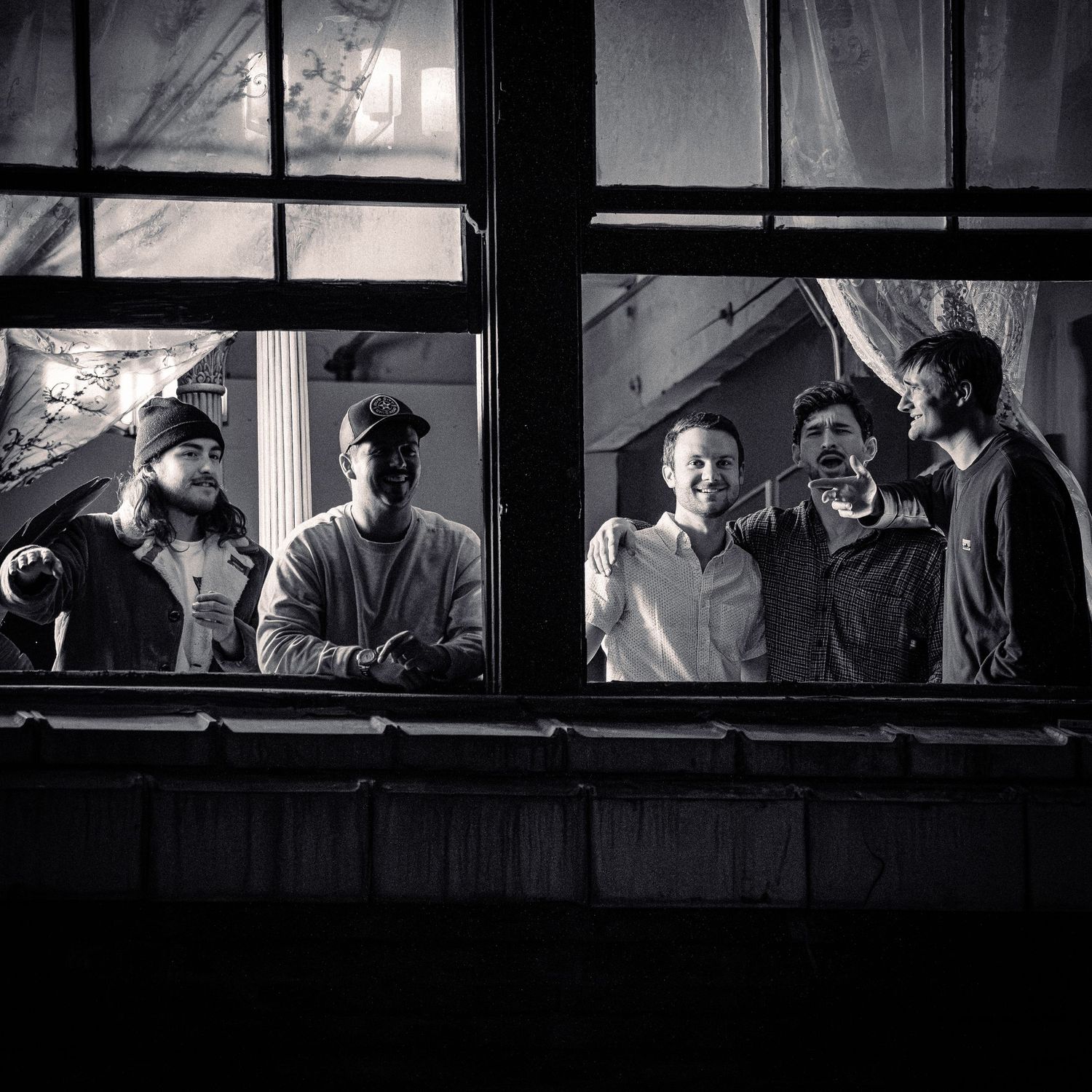 Night scene capturing silhouettes of people through illuminated building windows.