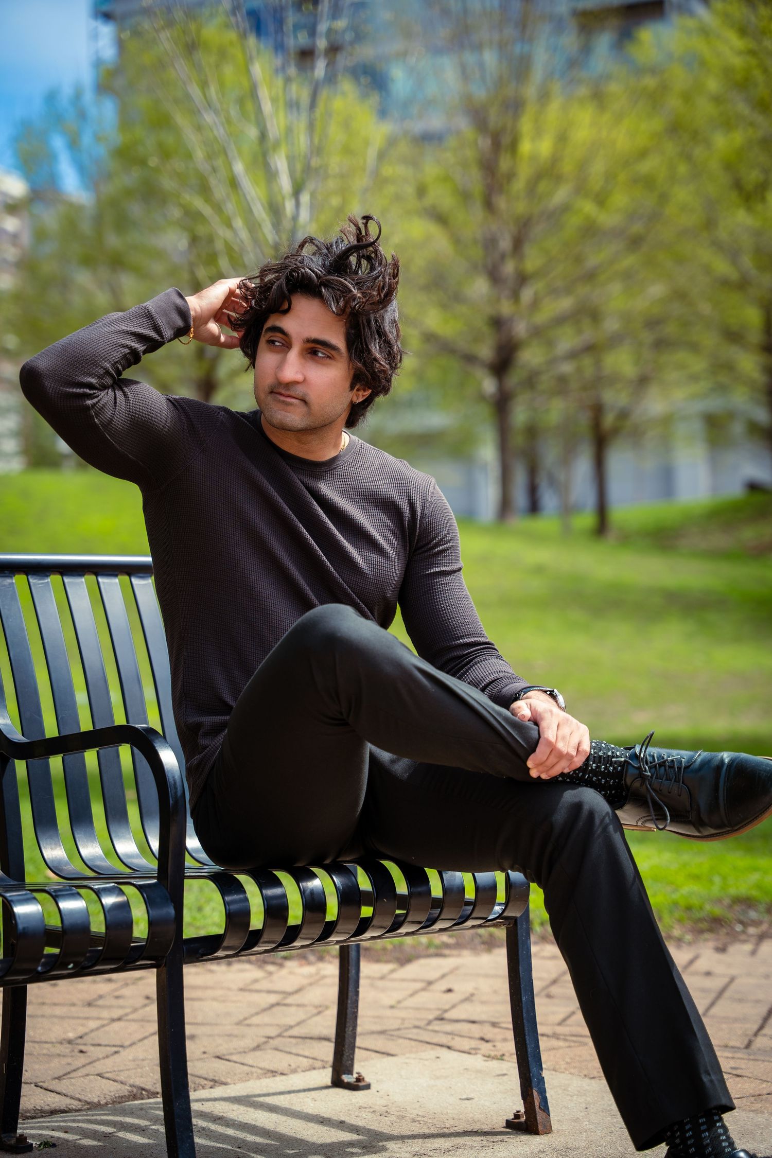 Person in dark suit relaxing on park bench during spring day.