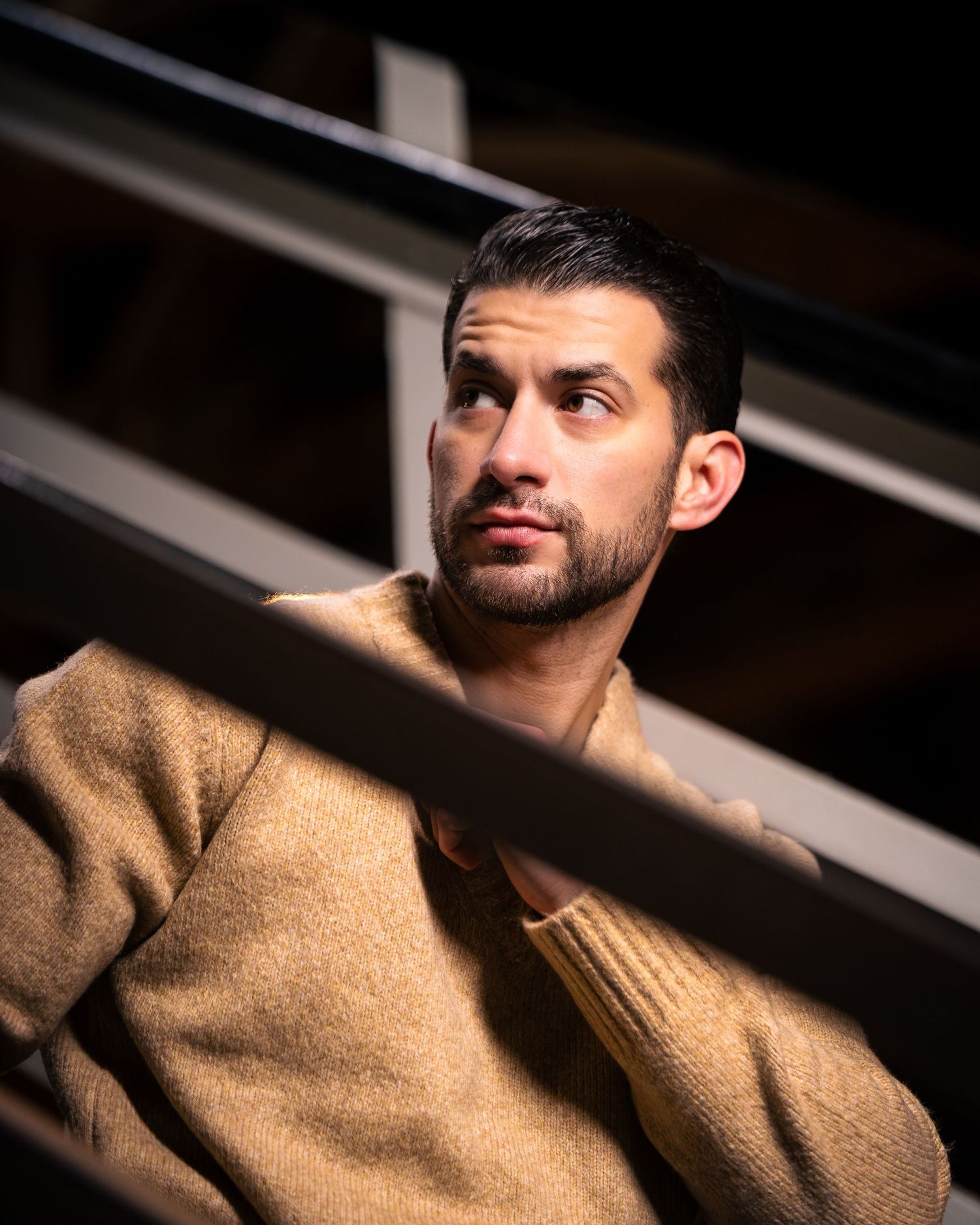 Dramatic lighting portraits of man in camel sweater with shadows and contrast.