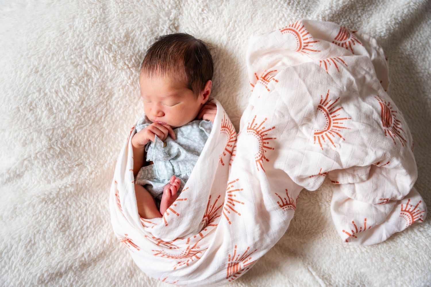 A series of newborn baby photos arranged in a row showing swaddled infant on white bedding with coral patterns.