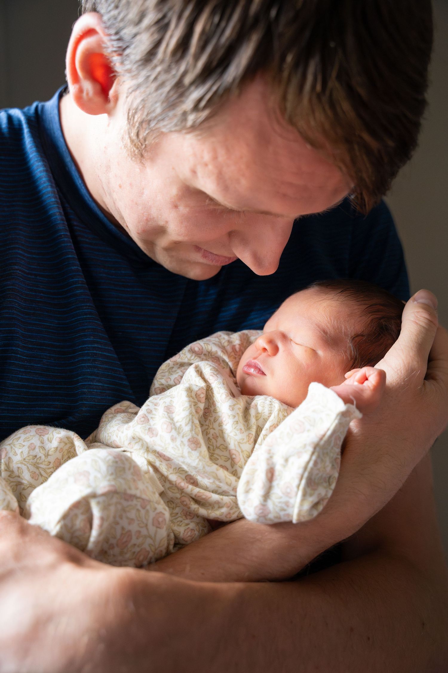 A tender moment captured in a series of photos showing a parent gently kissing their sleeping newborn baby in white clothing.