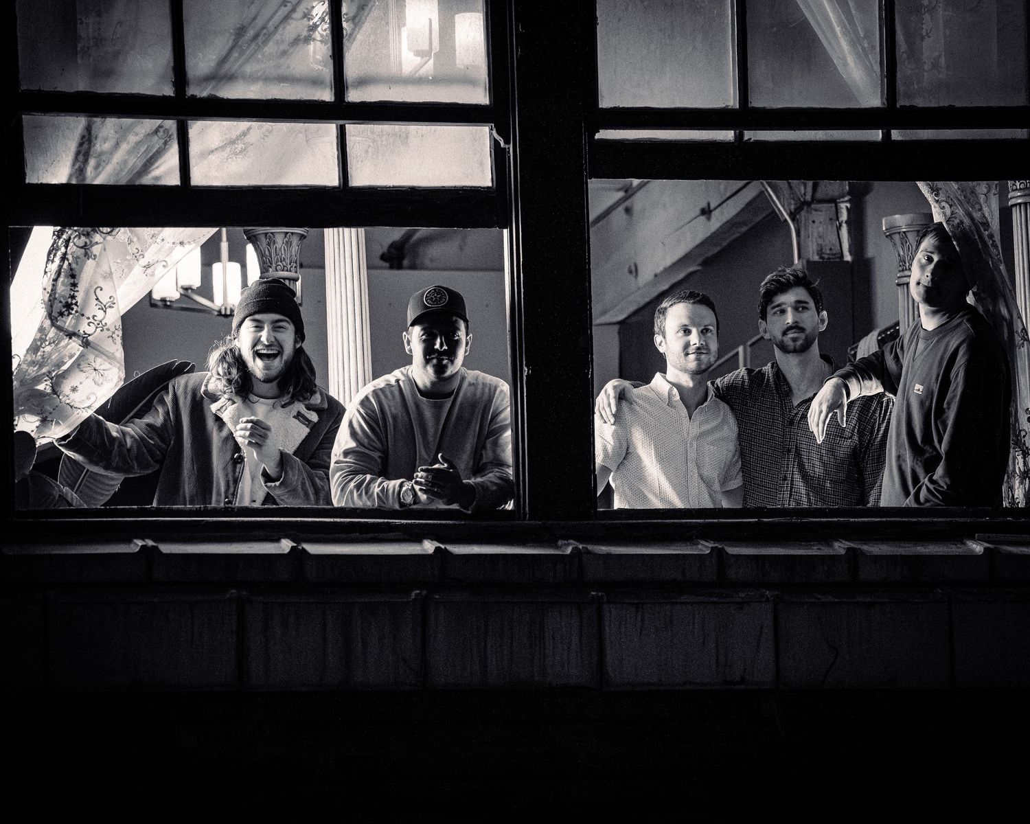 Silhouetted figures seen through series of windows in dramatic black and white composition.