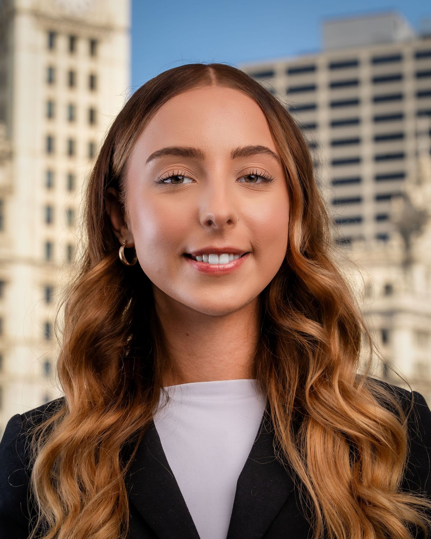 Corporate headshots featuring black blazer and white blouse against city backdrop.