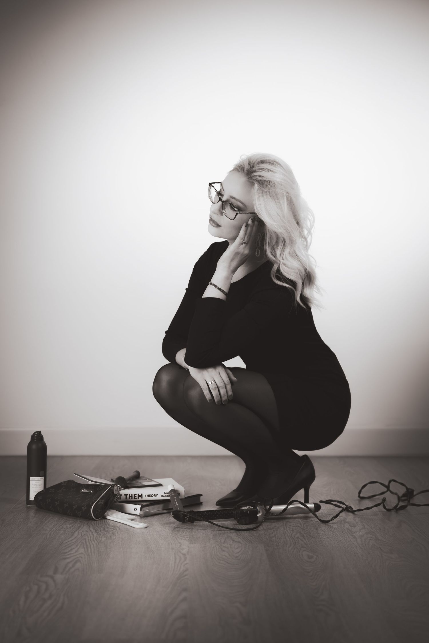 Black and white artistic photo series showing a figure in black crouched on wooden floor against white wall.