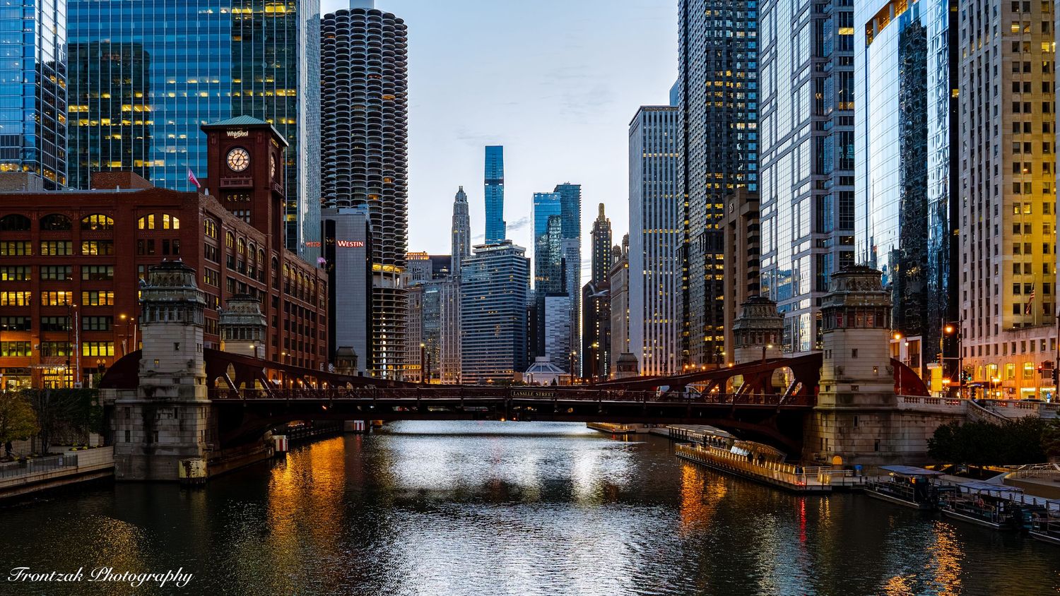 Illuminated Chicago cityscape at dusk with iconic bridge spanning the Chicago River between glass skyscrapers.