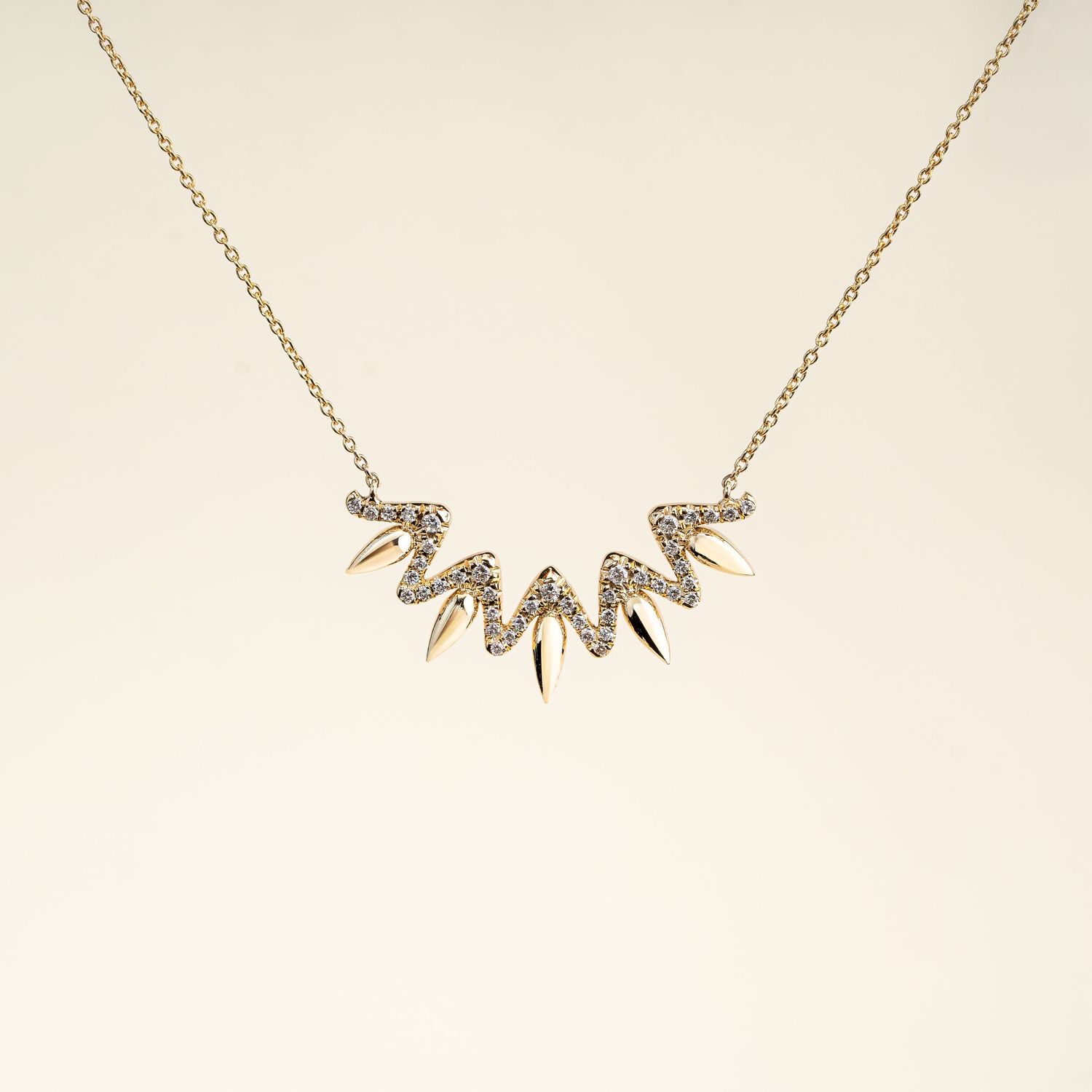 Geometric rose gold necklace with crystal spike pendants arranged in fan pattern.