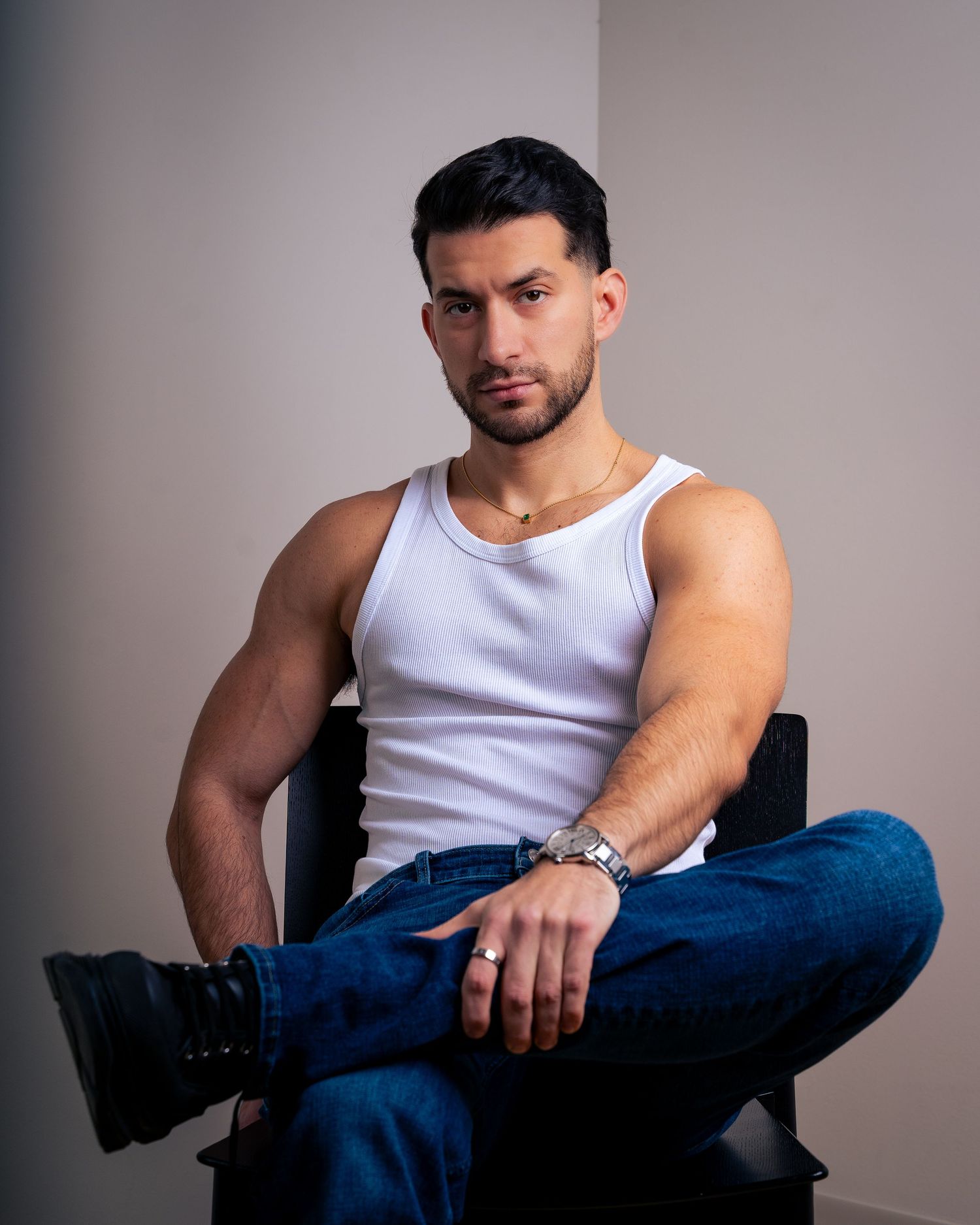Casual portrait series showing muscular arms in white tank top and dark denim jeans.