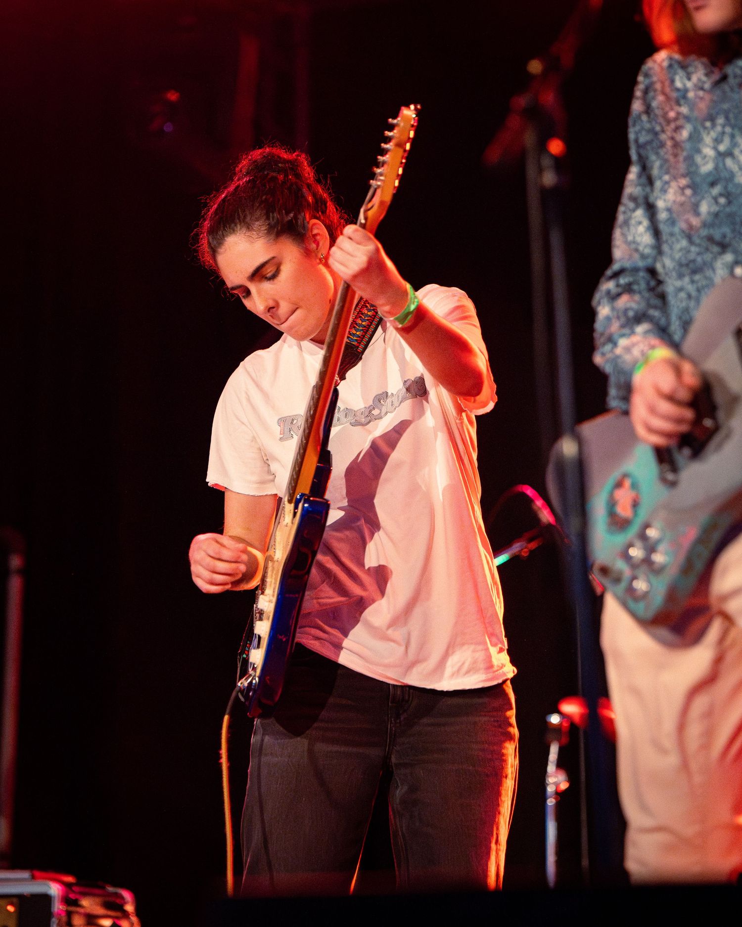 Musicians perform on stage with guitars under theatrical red lighting.
