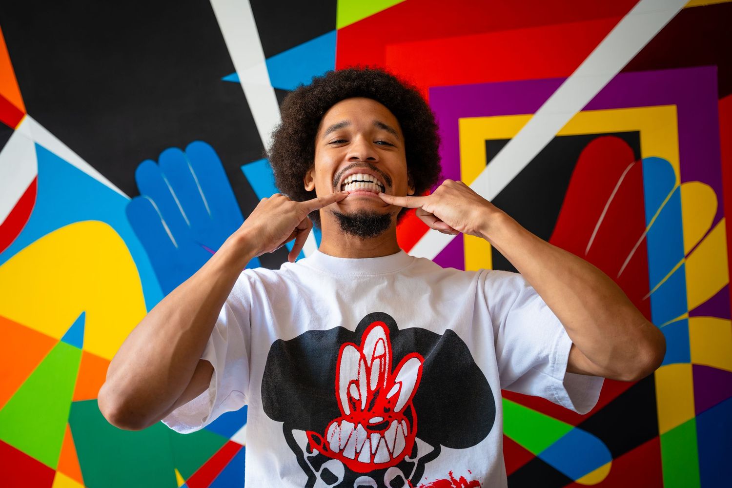 Person making animated expressions in front of colorful geometric wall art.