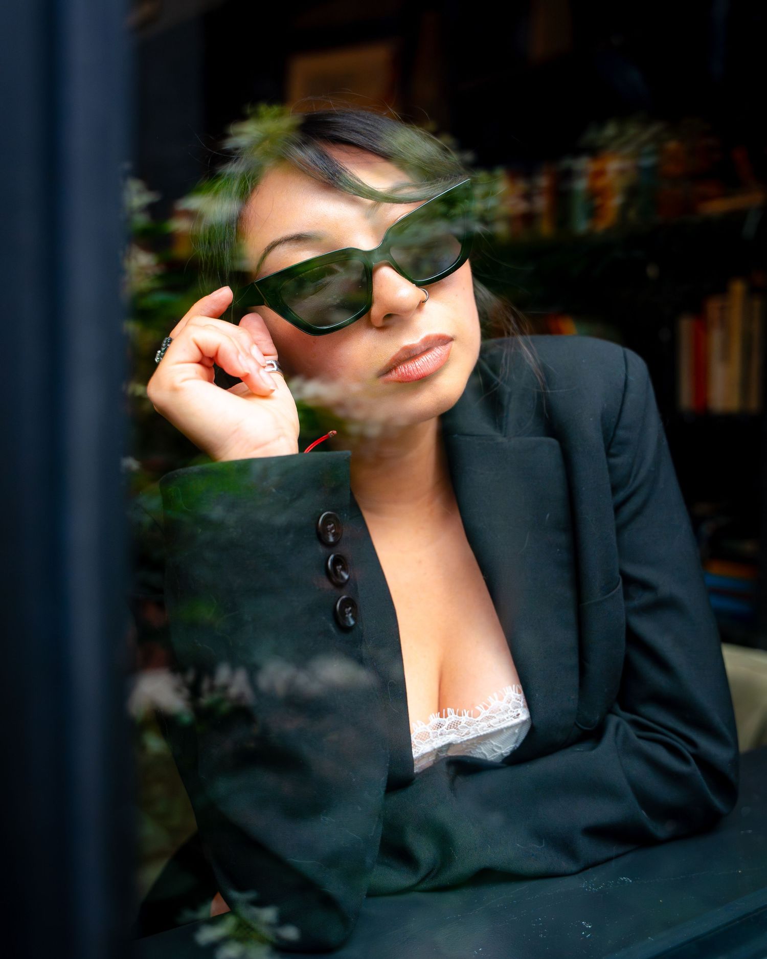 Fashionable portrait with sunglasses and black blazer in library setting.
