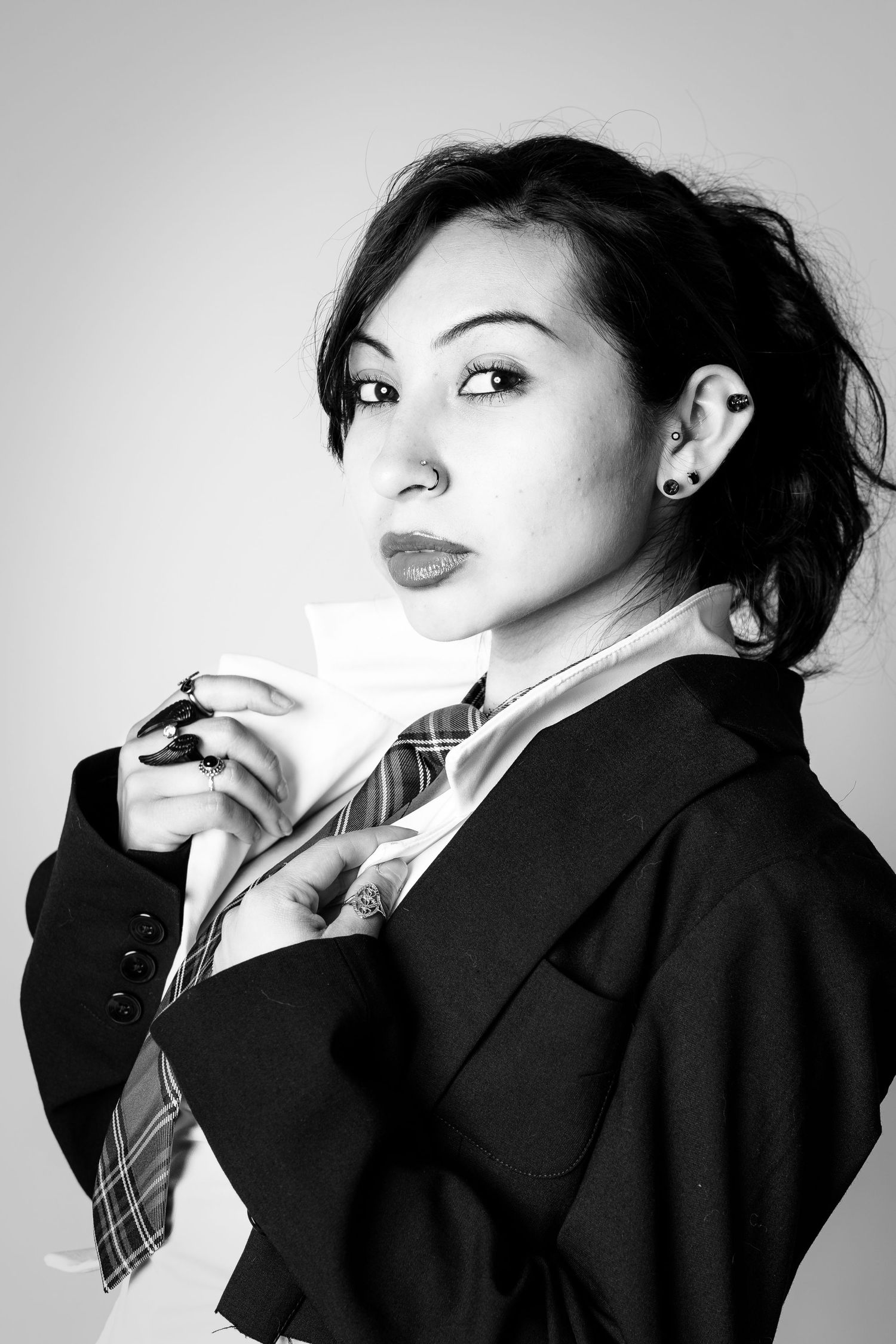 Fashion model poses dramatically in black and white portrait series wearing dark blazer and tie.