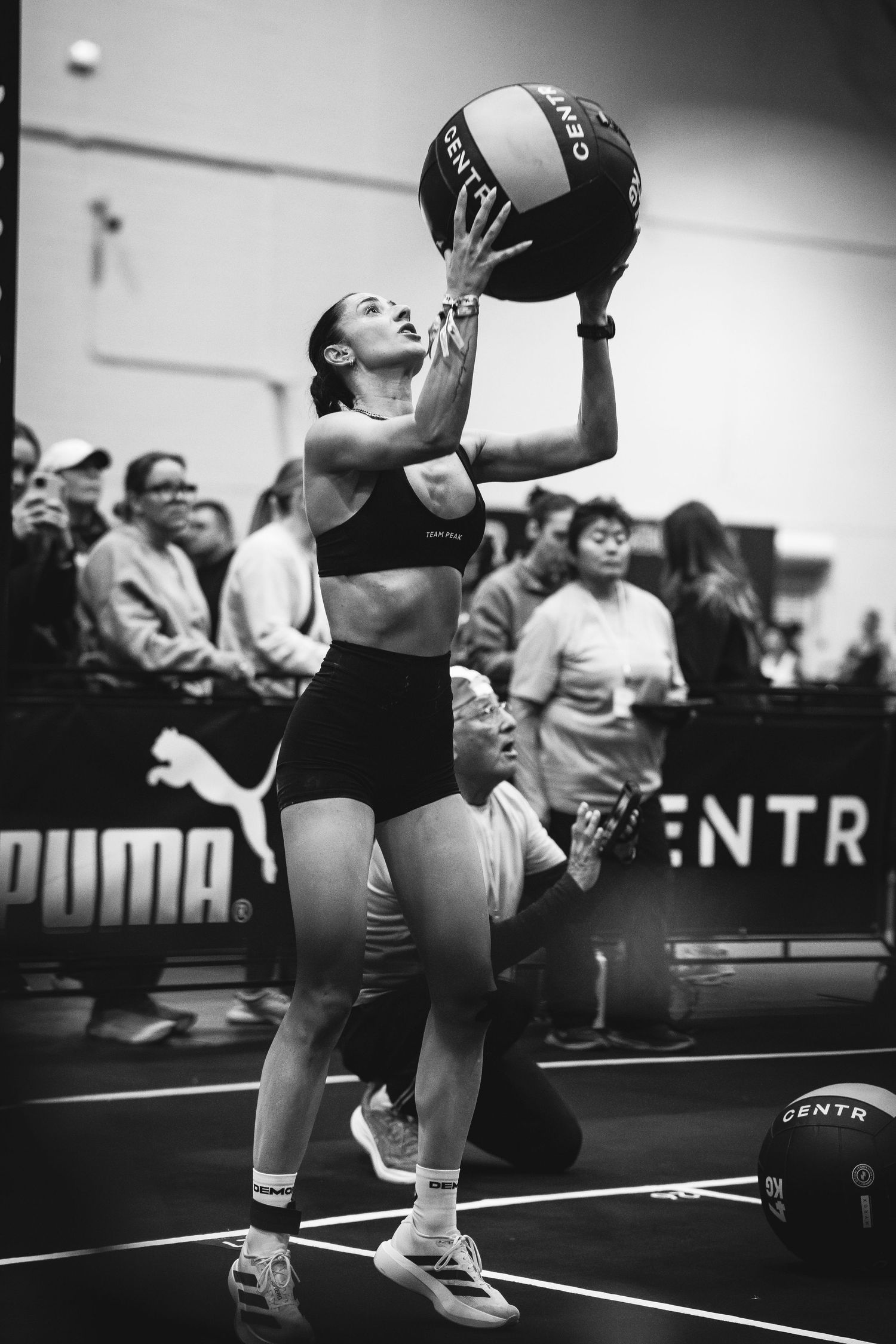 Athletes lift weights during a competition in a monochromatic setting.