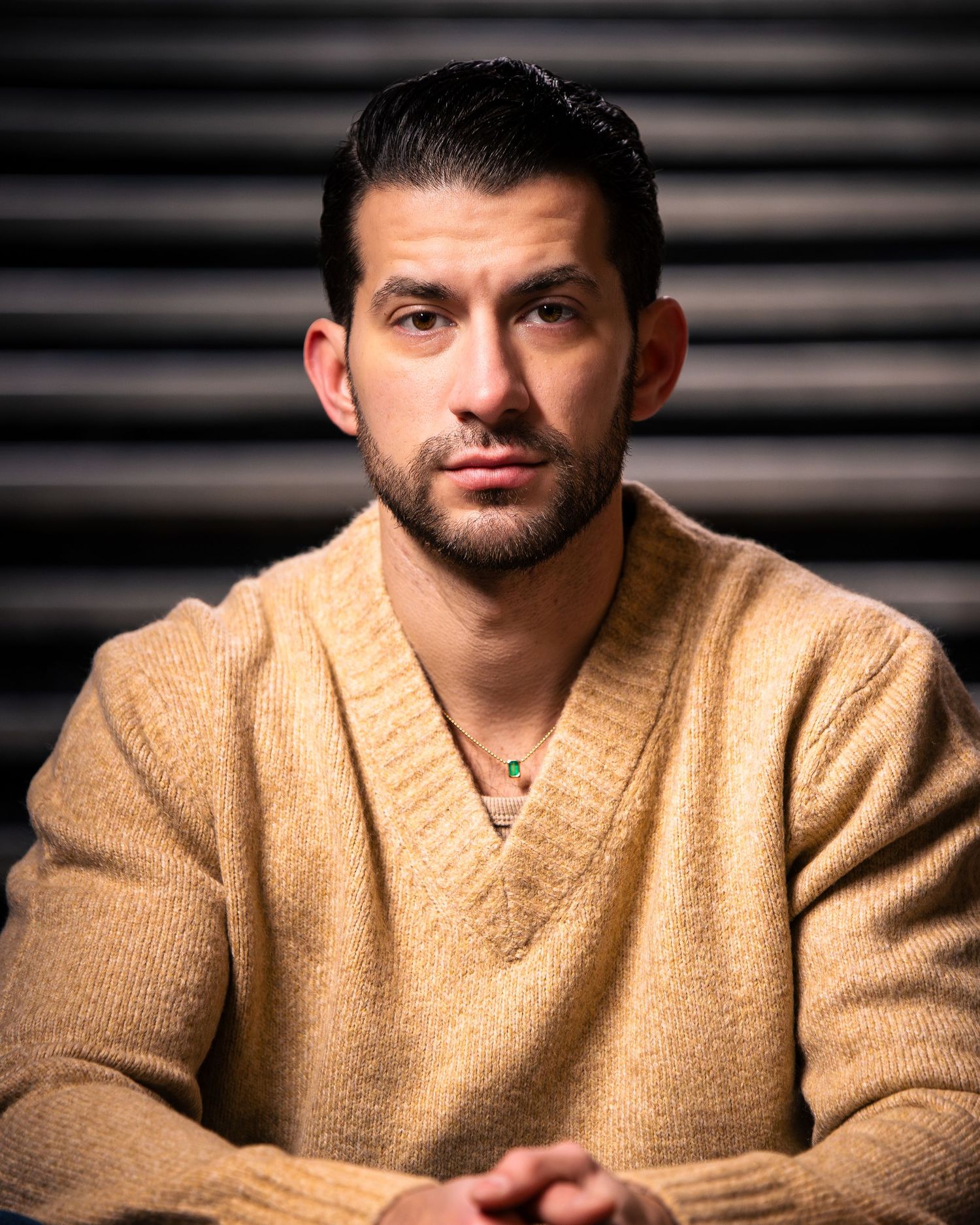 Series of headshots featuring a person wearing a tan v-neck sweater against dark backdrop.