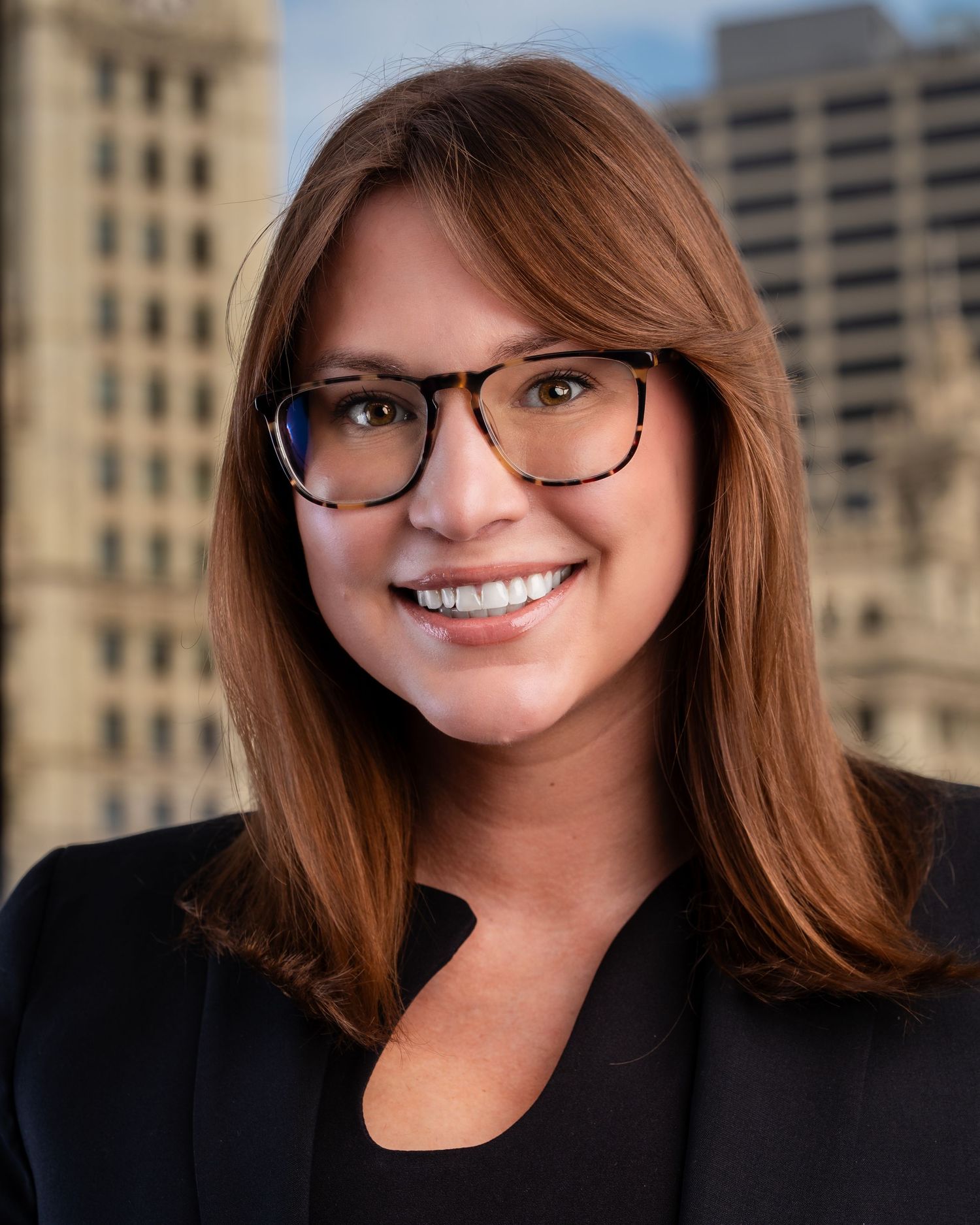 Professional headshots showing warm smiles against an urban office building backdrop.