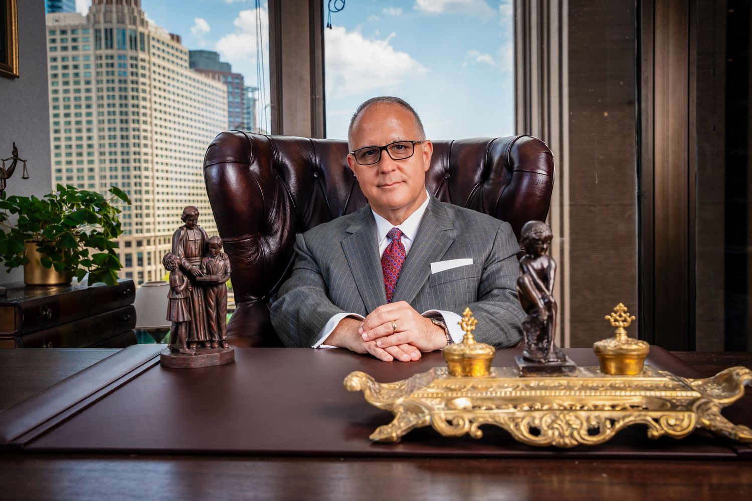 Modern executive office featuring ornate desk details and city views through large windows.