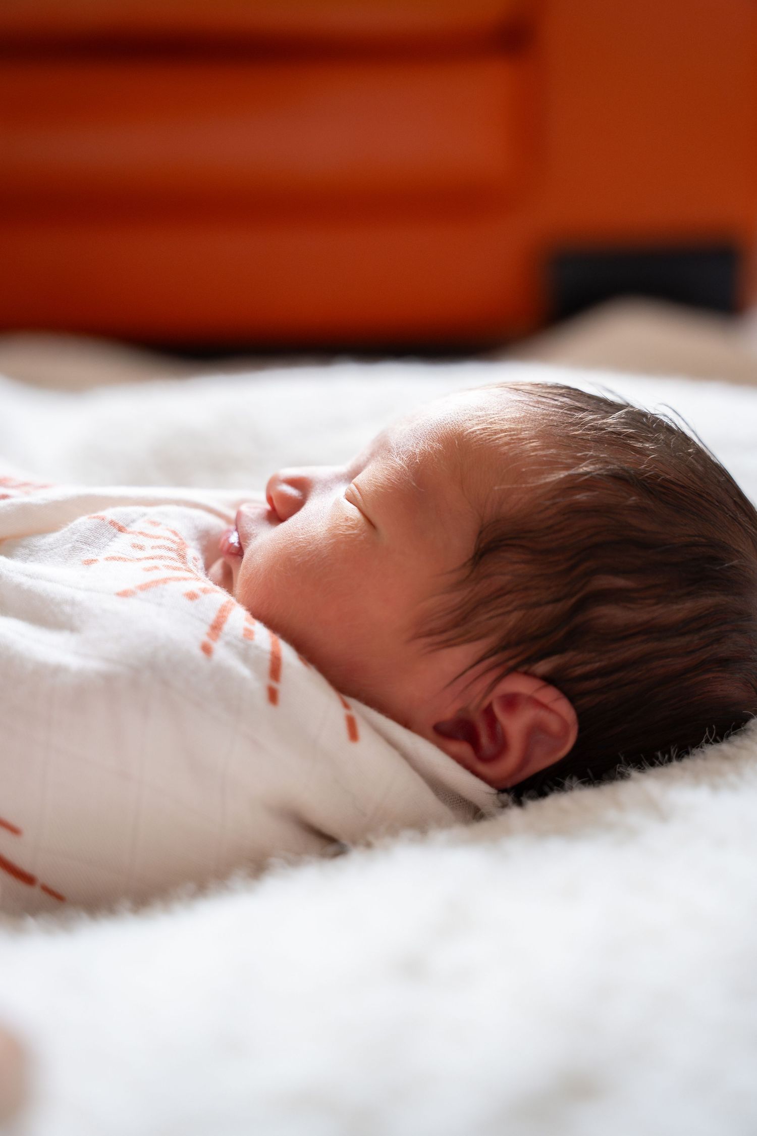 Sleeping infant wrapped in soft white blankets resting on cozy bedding.