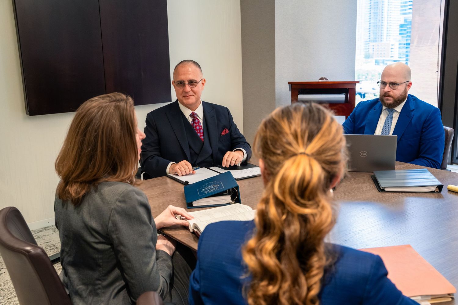 Corporate team meeting with professionals discussing documents around conference table.