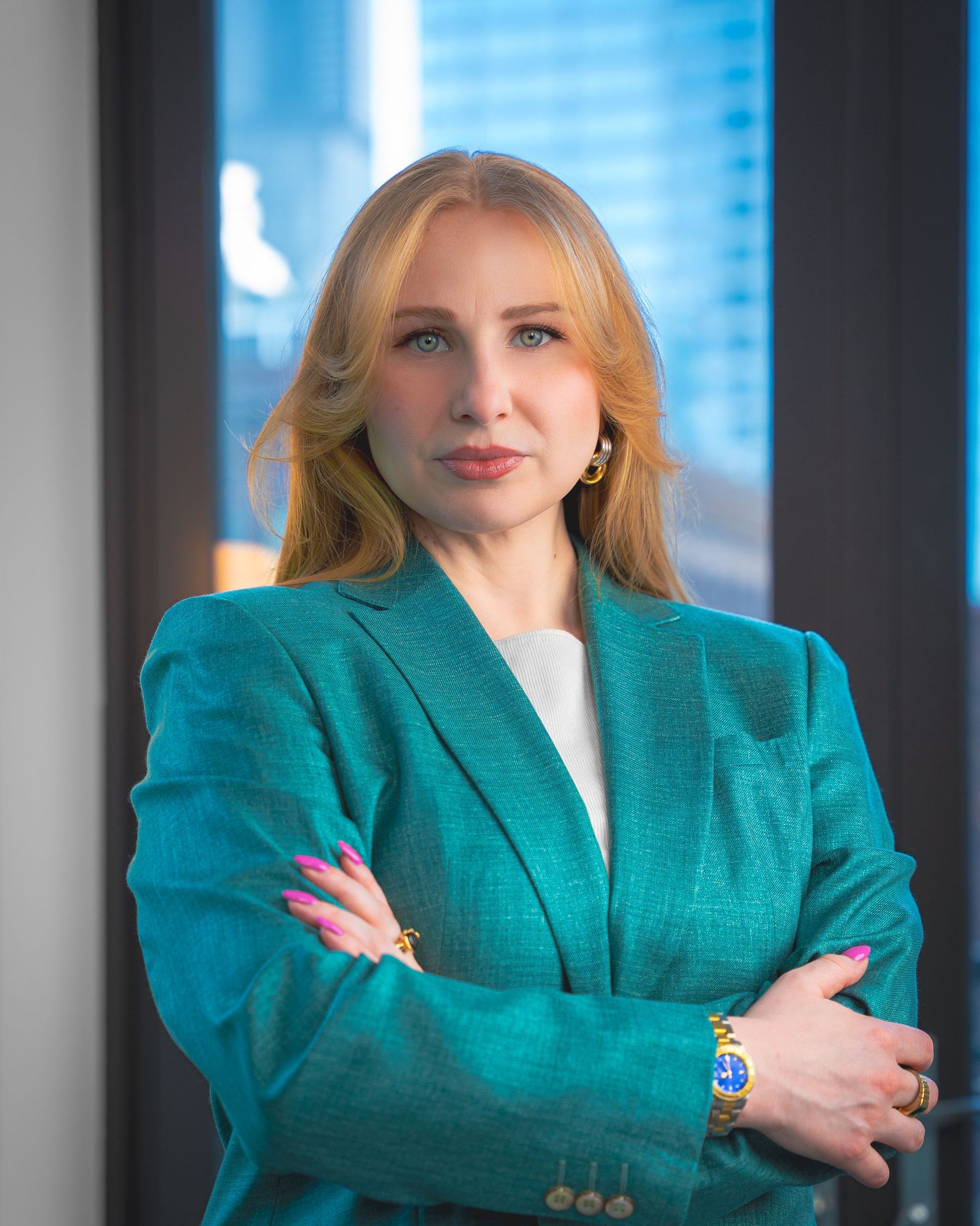 A person in a bright teal blazer strikes various poses against a window with city views in the background.