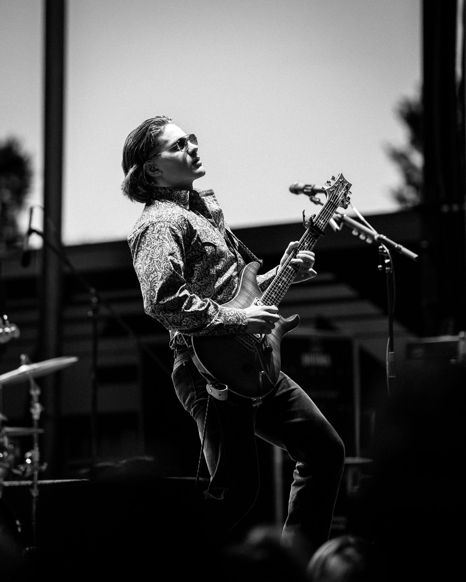 Dramatic black and white performance shot of musician playing passionately on stage.