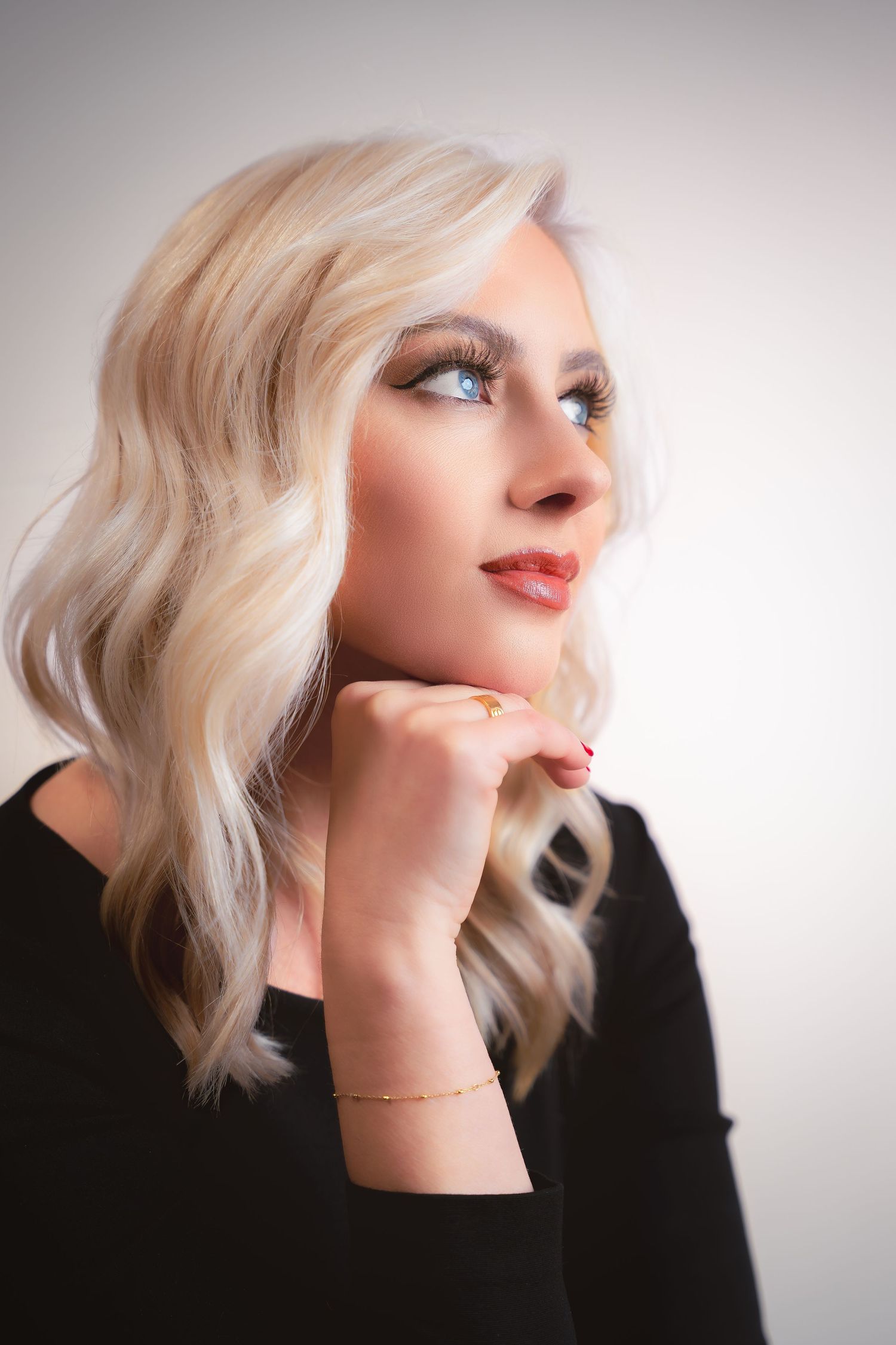 Artistic portrait series in profile view showing platinum blonde hair and black clothing against white backdrop.